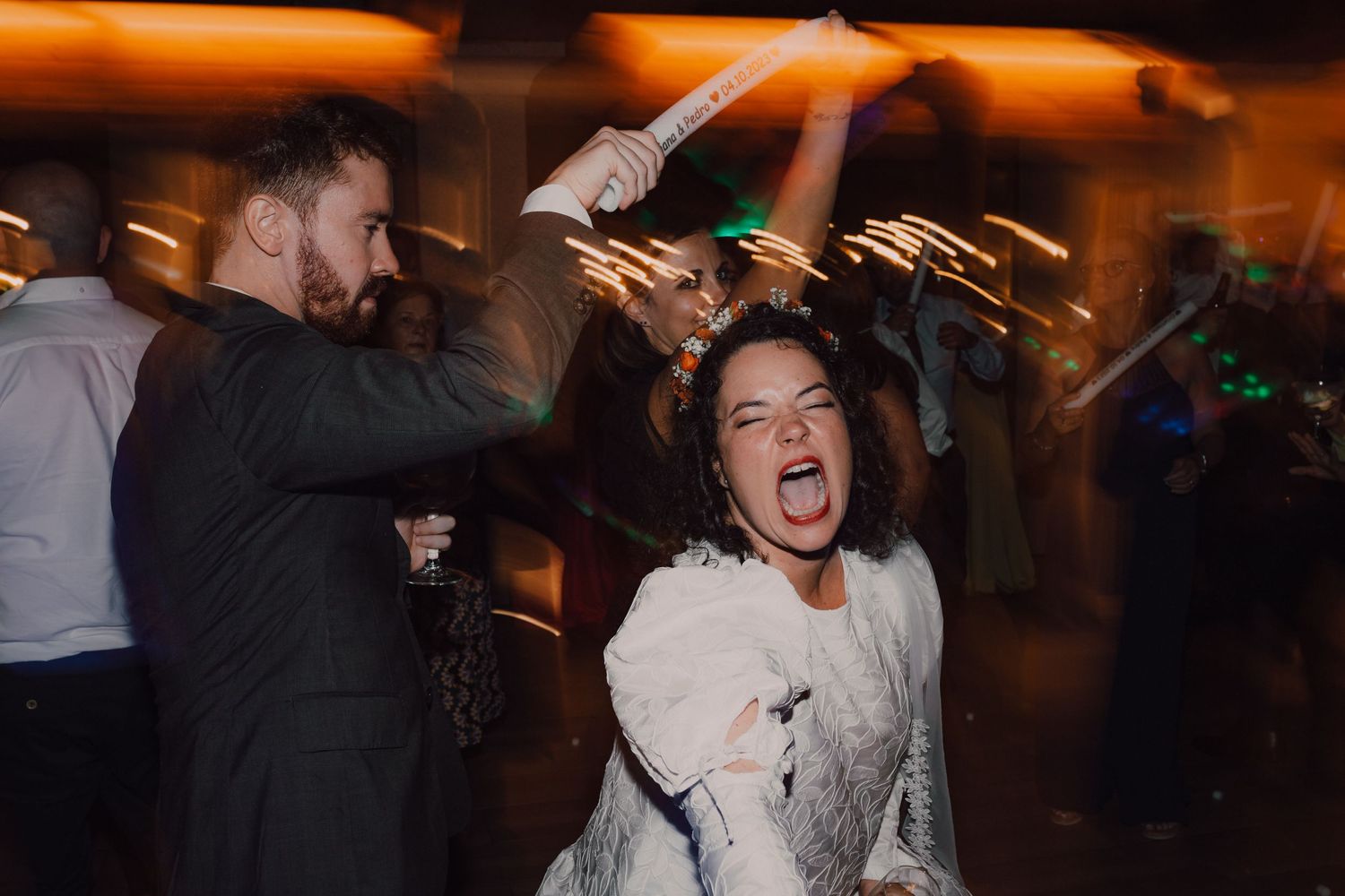 Wedding reception dance party with guests enjoying dynamic movement under warm lighting.