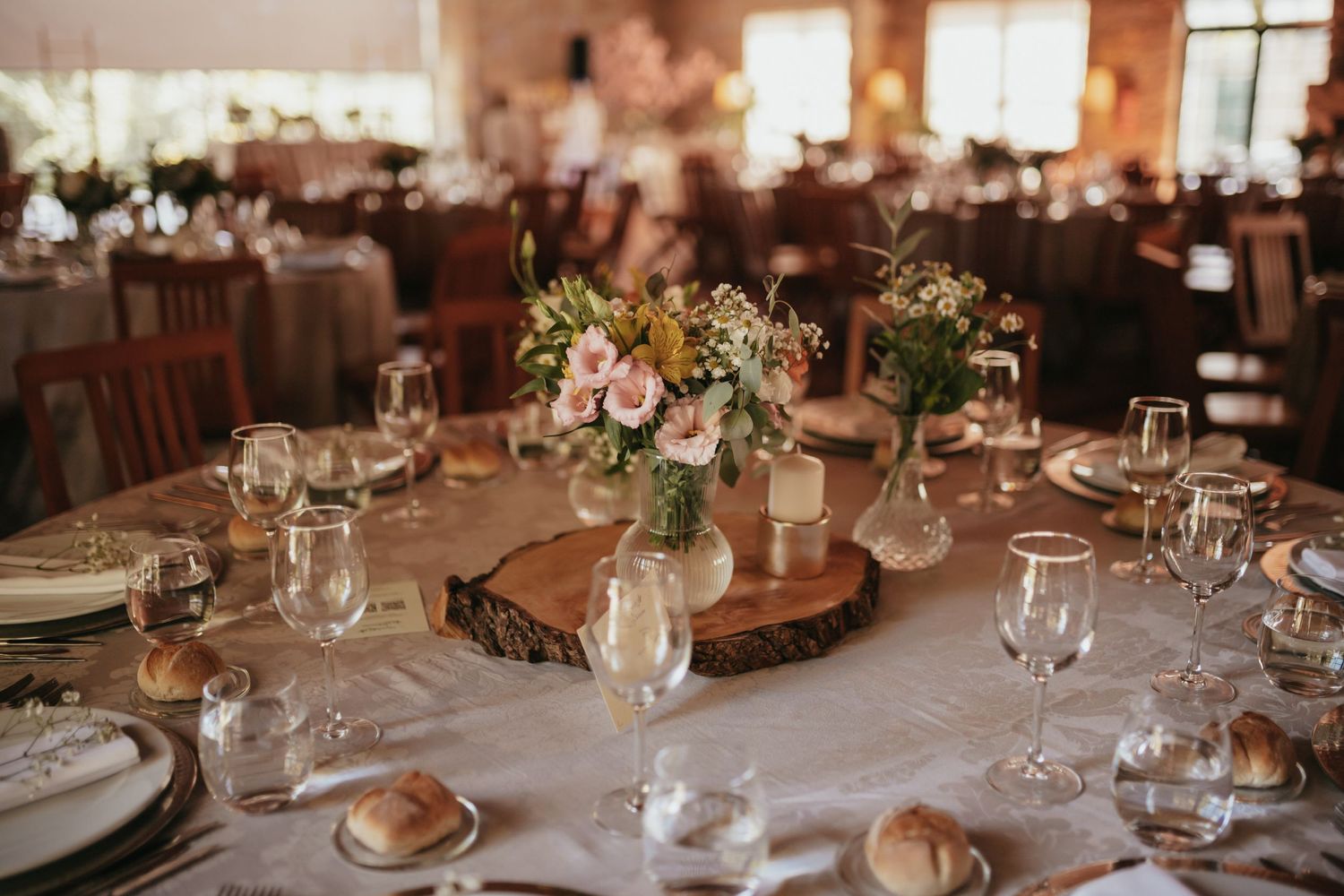 Elegant wedding reception table setting with floral centerpieces and rustic wood accents.