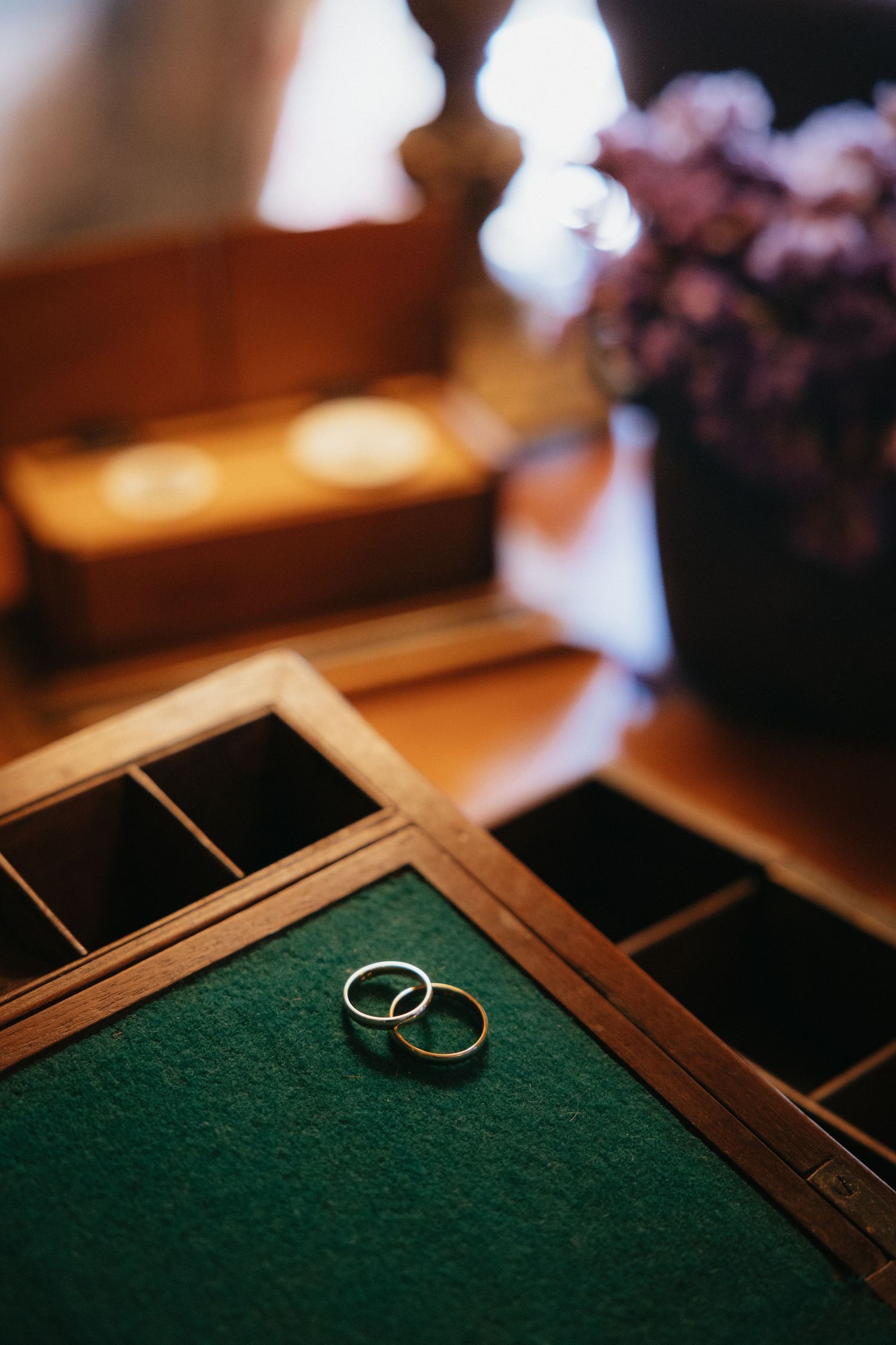 Wedding rings displayed on green felt surface in wooden jewelry box.