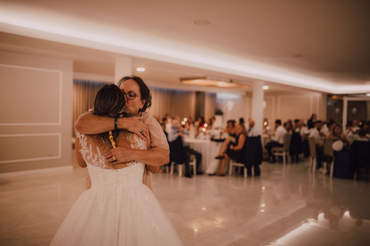 Wedding couple sharing an intimate dance moment during their reception in a softly lit ballroom.