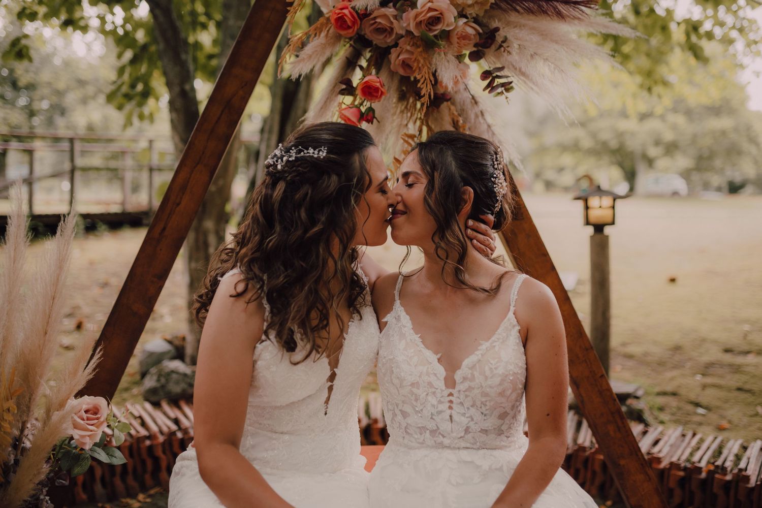 A romantic moment captured under a decorated arch with pampas grass and dried flower arrangements.