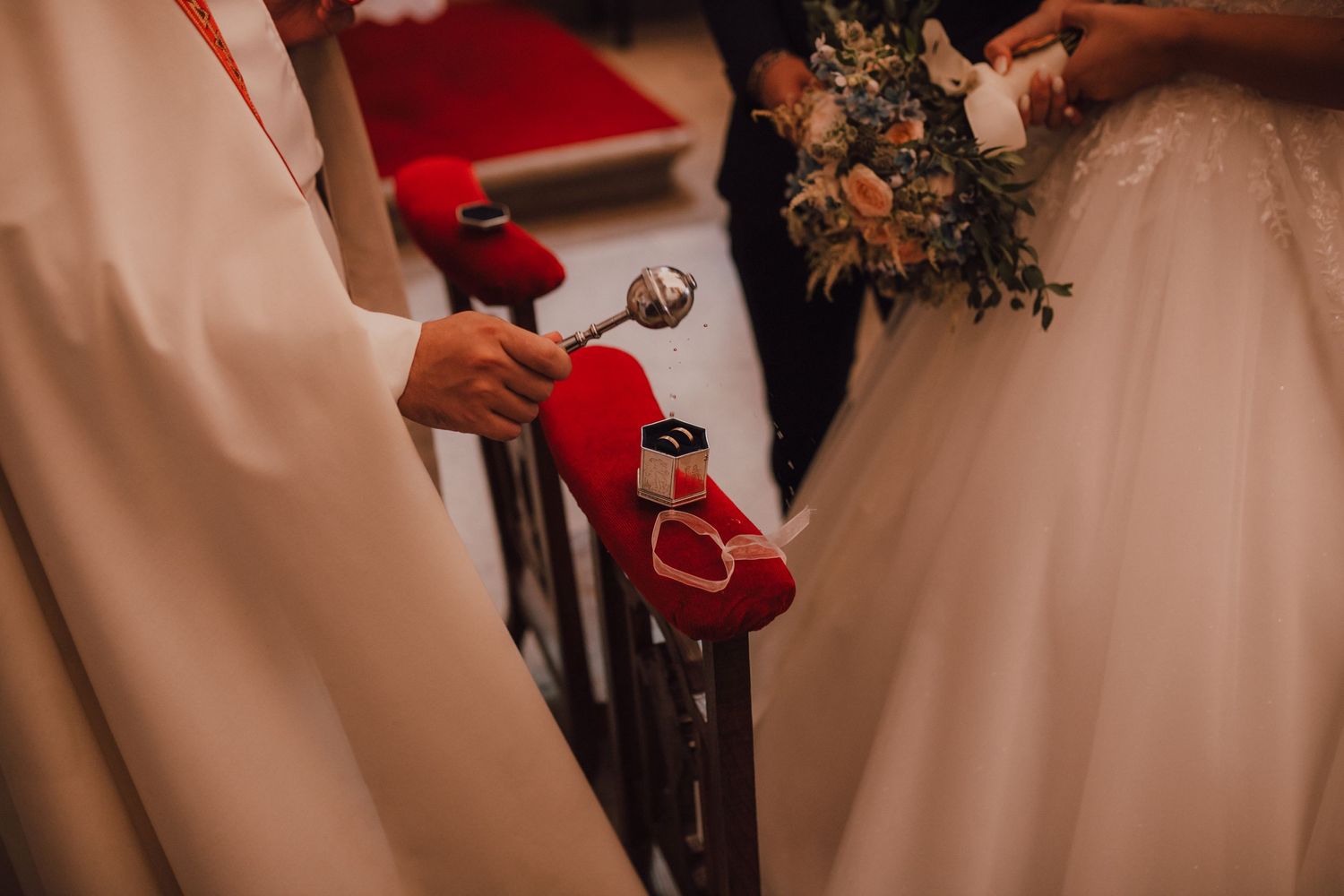 Close-up of wedding ceremony details with red velvet ring box.