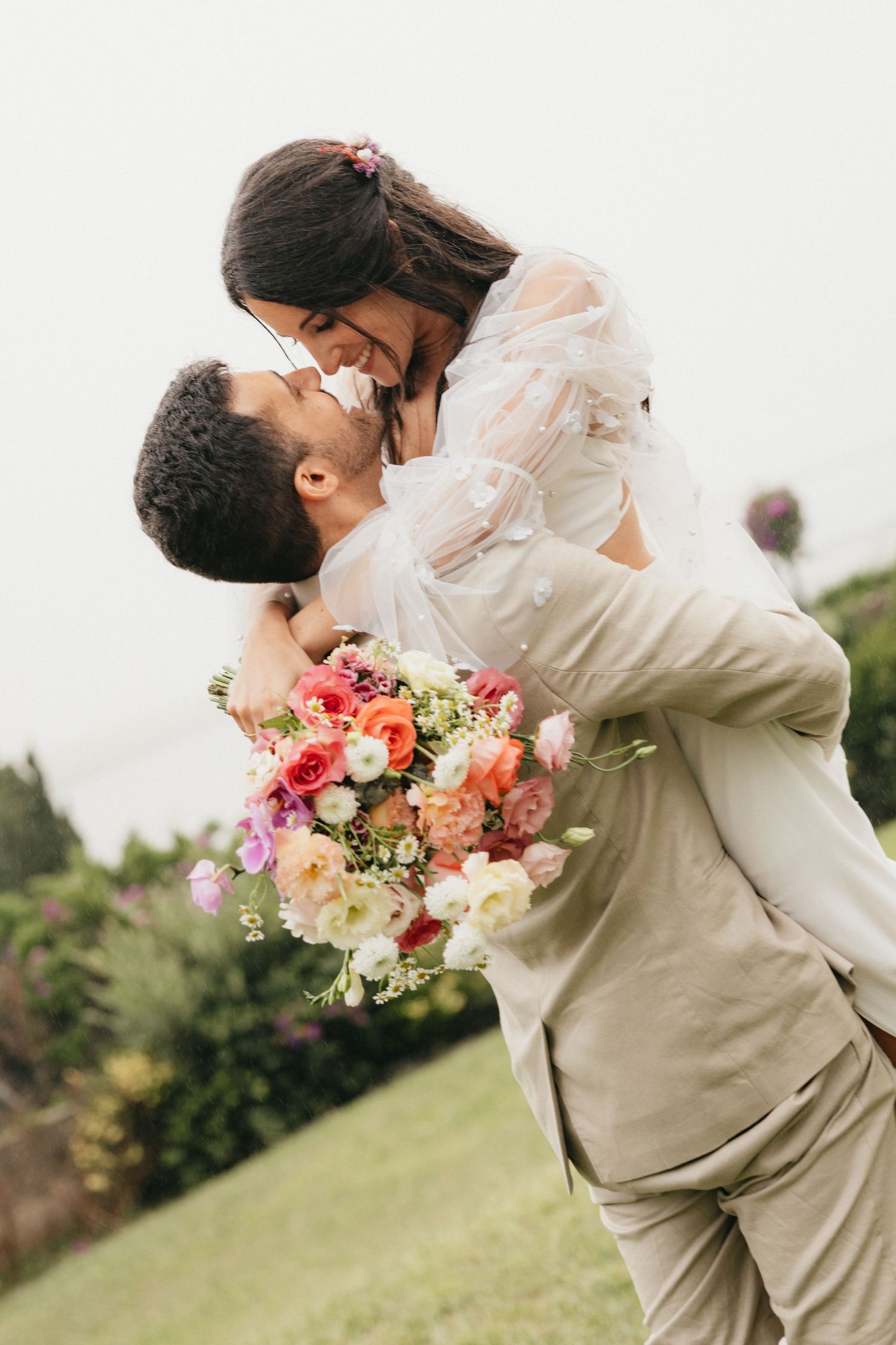 Joyful wedding moment captured with colorful bouquet in outdoor garden setting.