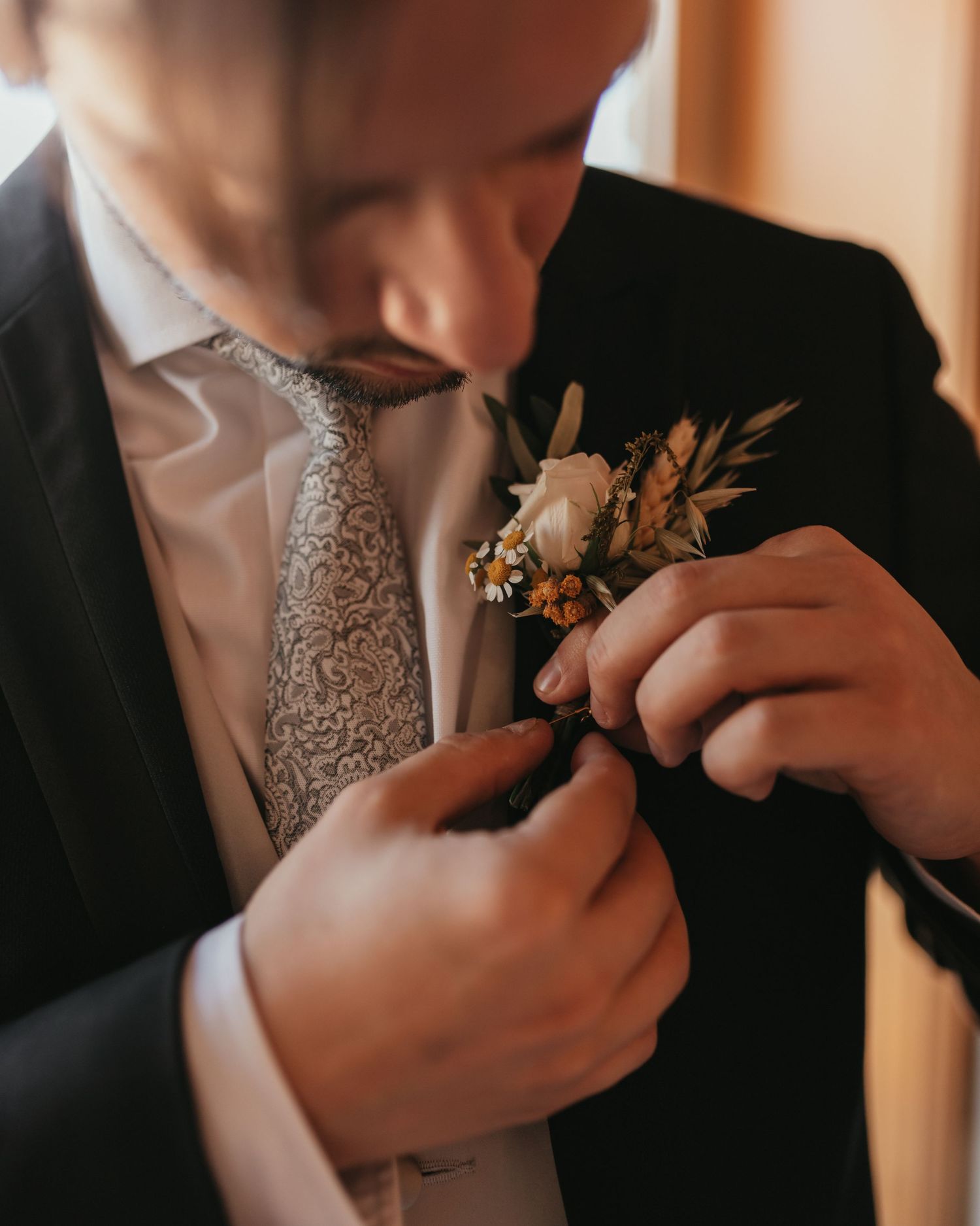 Close-up shot of adjusting a floral boutonniere on a formal suit.