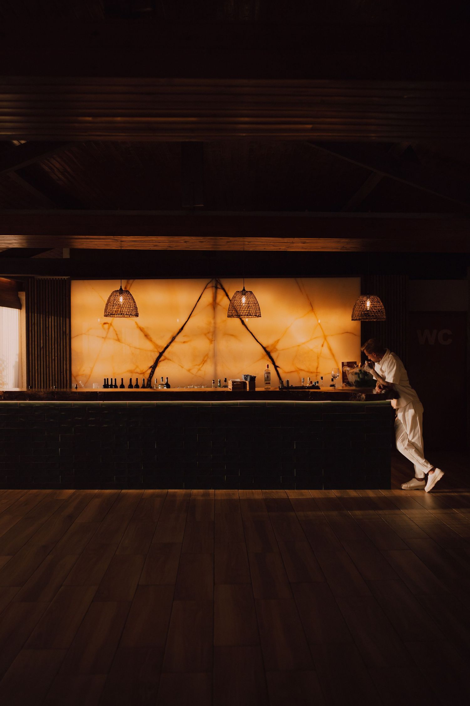 Moody interior shot of an illuminated bar counter with pendant lighting.