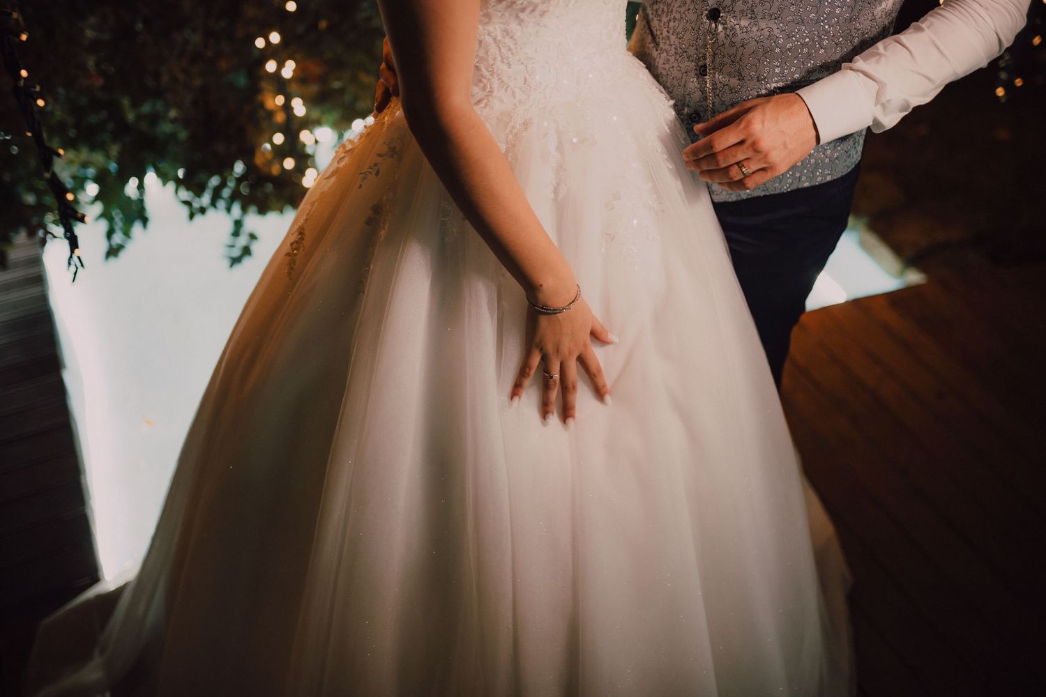 Close-up detail of bride's gown and hands during wedding celebration.
