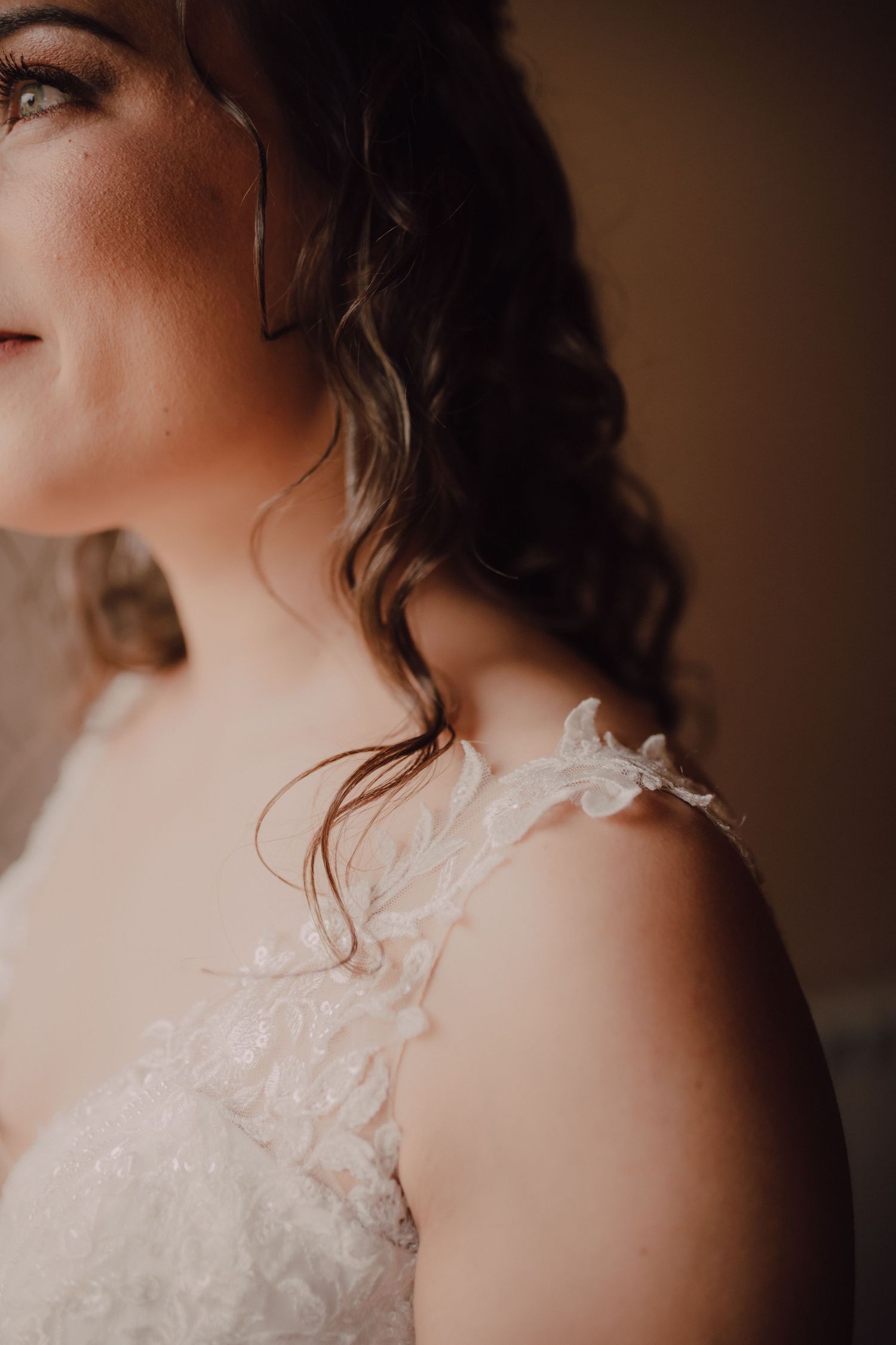 Close-up detail of delicate lace on an ivory wedding dress shoulder.