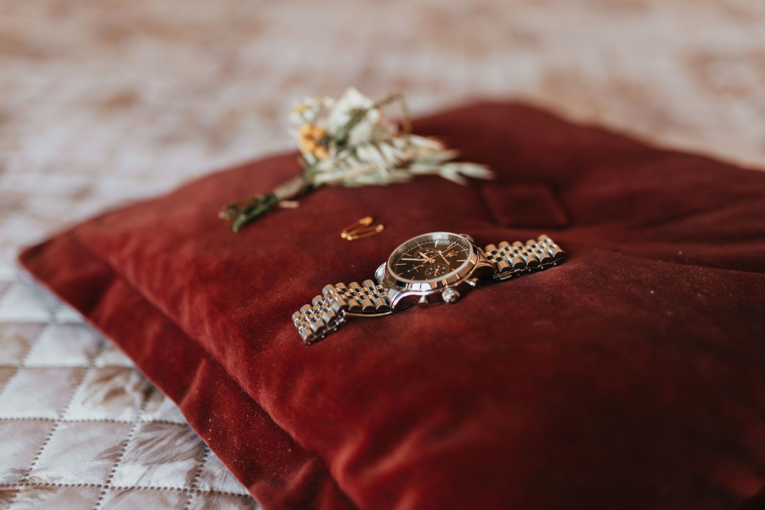 Wedding rings and jewelry displayed on plush red velvet pillow.