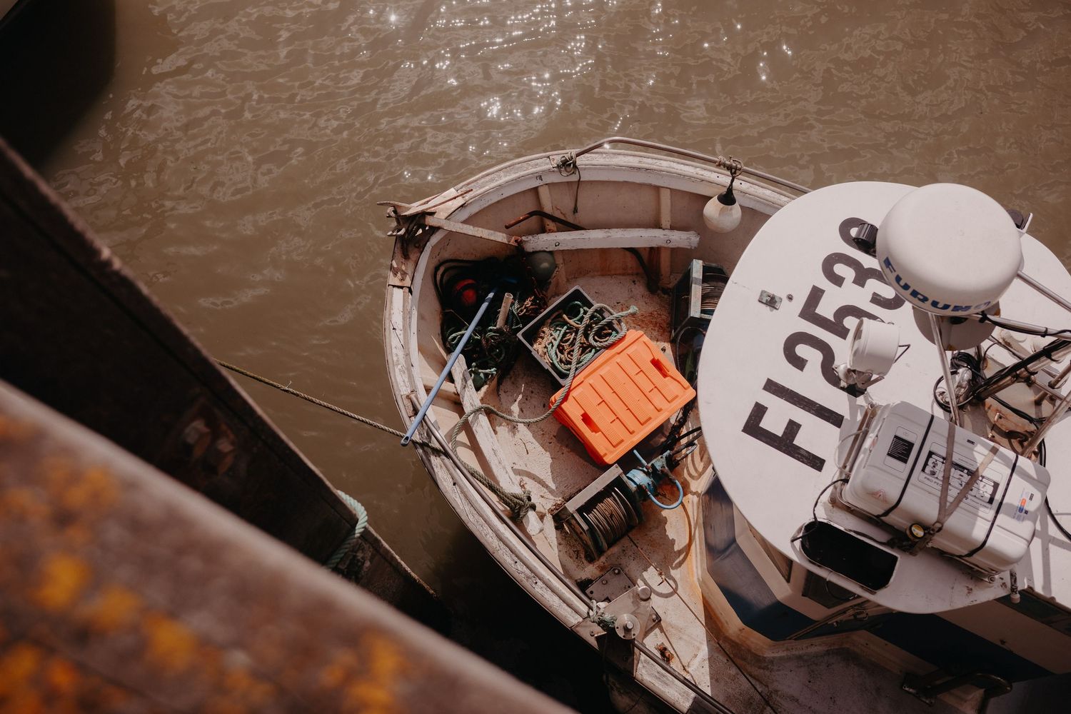 Aerial view of commercial fishing boat with fisher number visible on white deck and orange gear visible.
