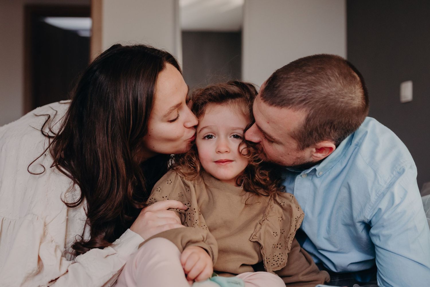 Family of three sharing tender kisses and embraces in a series of intimate black and white portraits.