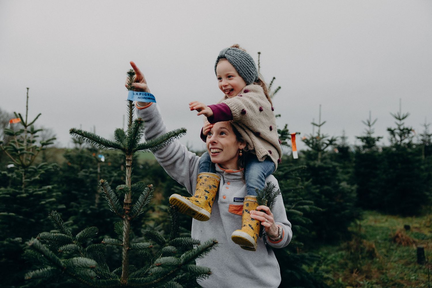 Couple holding hot beverages outdoors at a Christmas tree farm on a cold winter day.