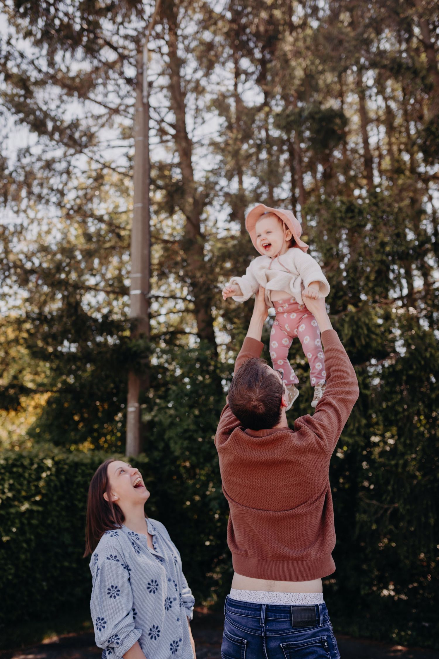A family enjoys playful moments together outdoors in a forest setting during golden hour.