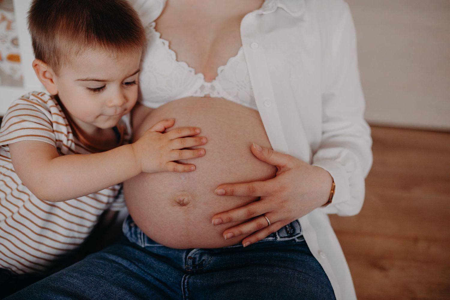 A tender moment of breastfeeding with a white shirt and wooden floor in the background.