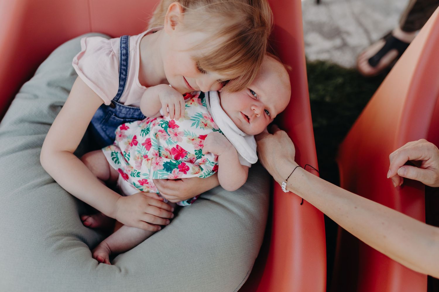 A person in a red dress breastfeeding their baby while sitting on a red couch.