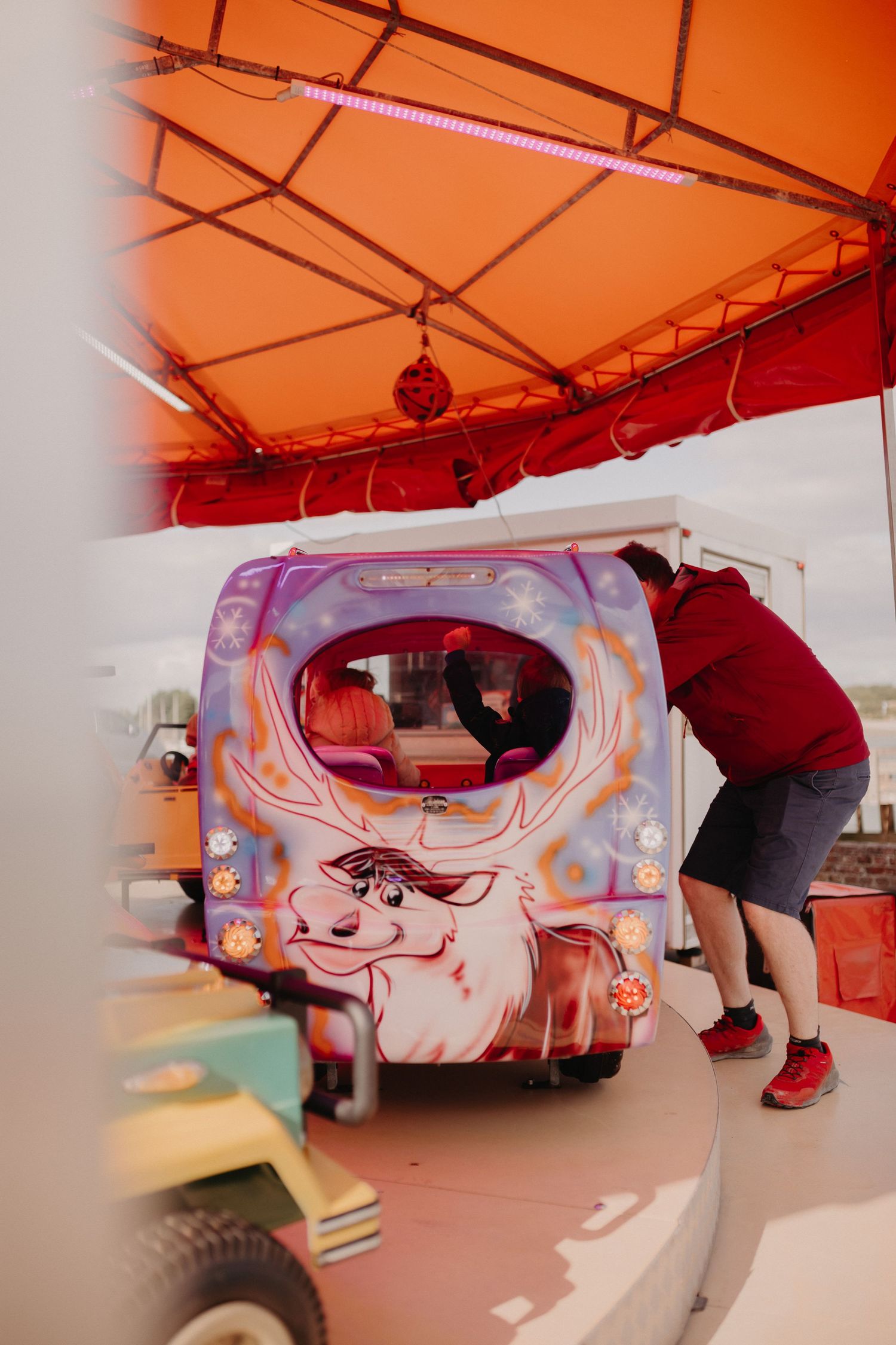 Someone leans into a colorfully decorated pink food truck with artistic illustrations and ambient lighting.