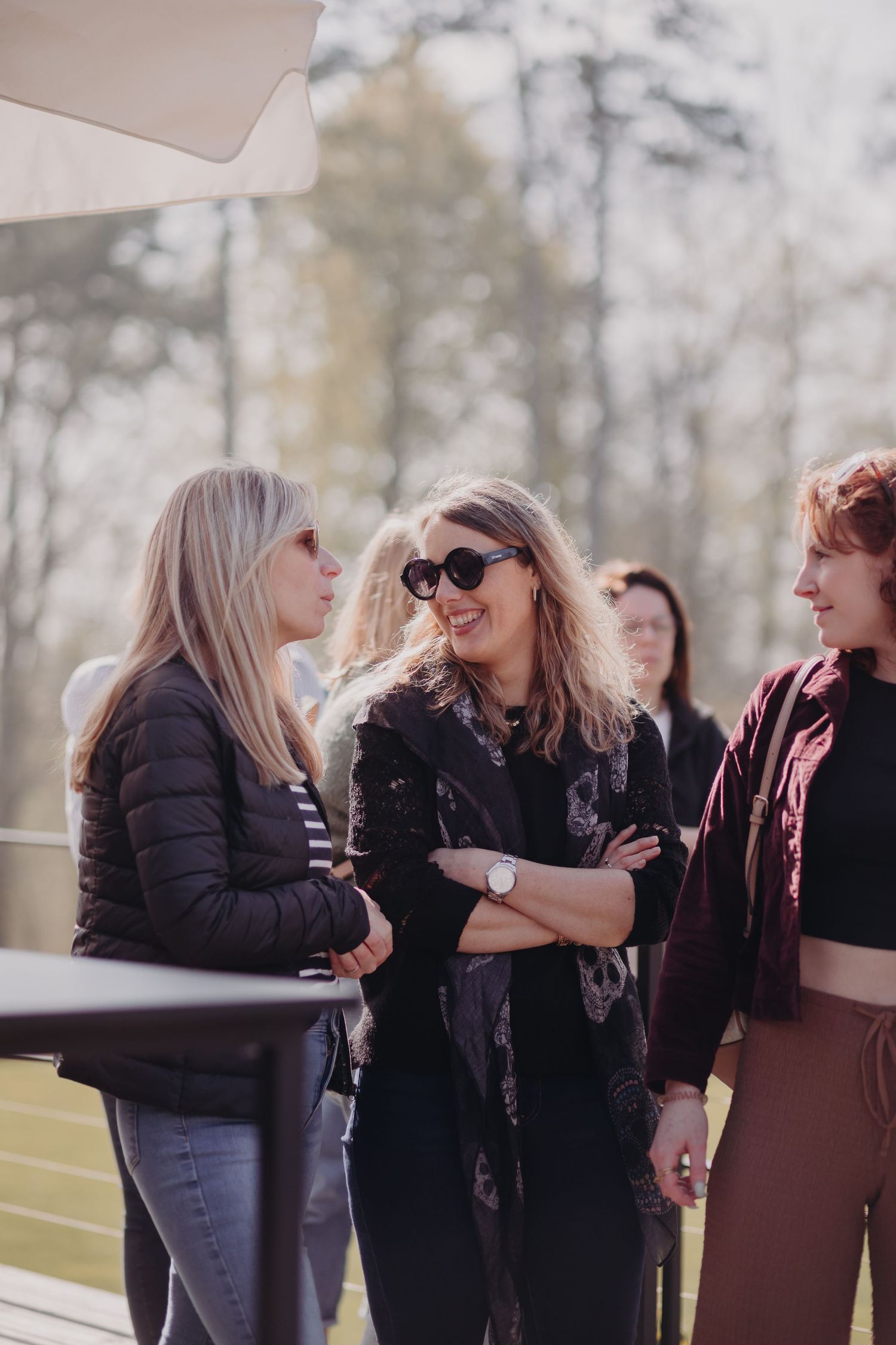 Group of friends having an animated conversation outdoors on a sunny day while enjoying casual social time together.