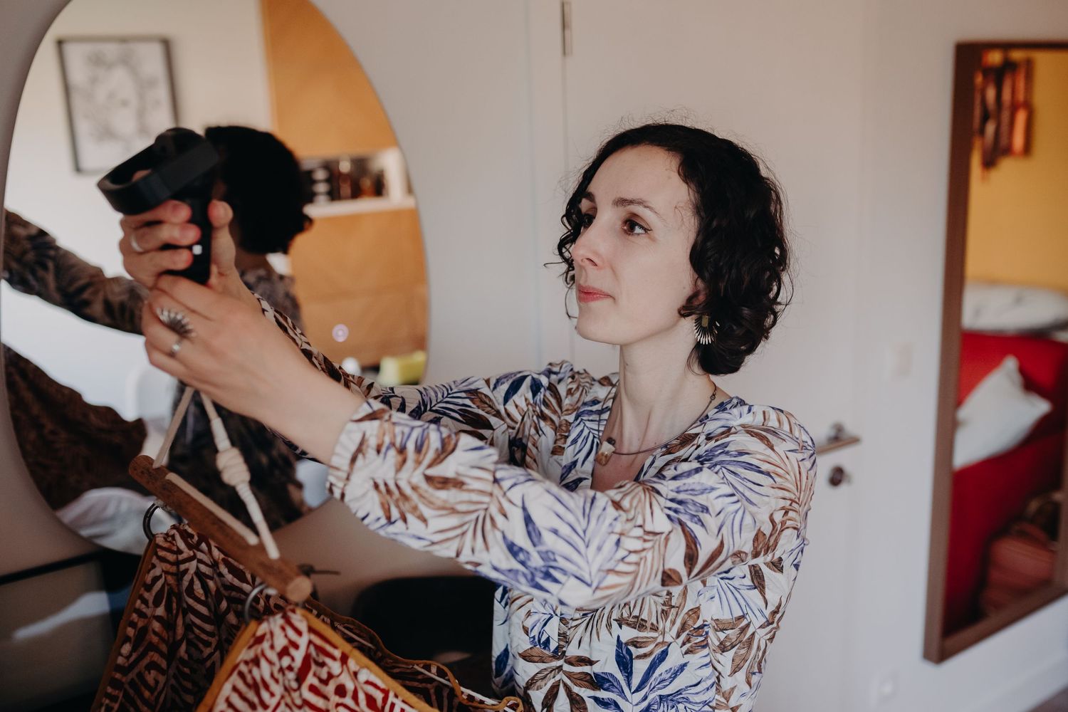 A person in a floral print dress holds up a small black dog while sitting in a living room.