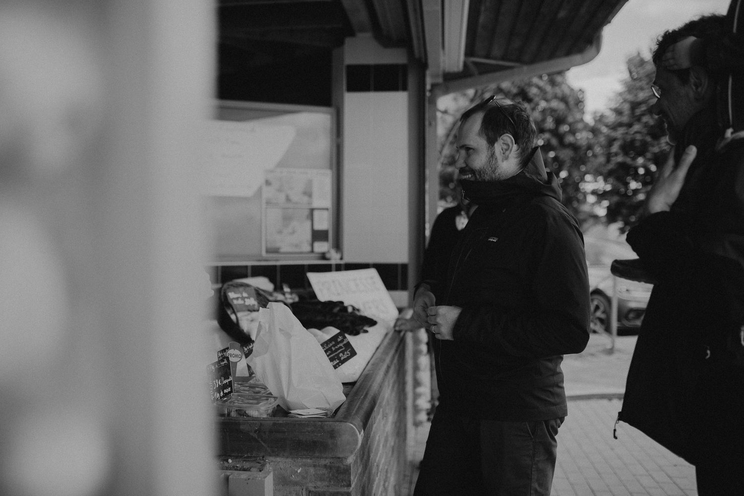 A person wearing dark clothing stands at a counter in a black and white photograph.