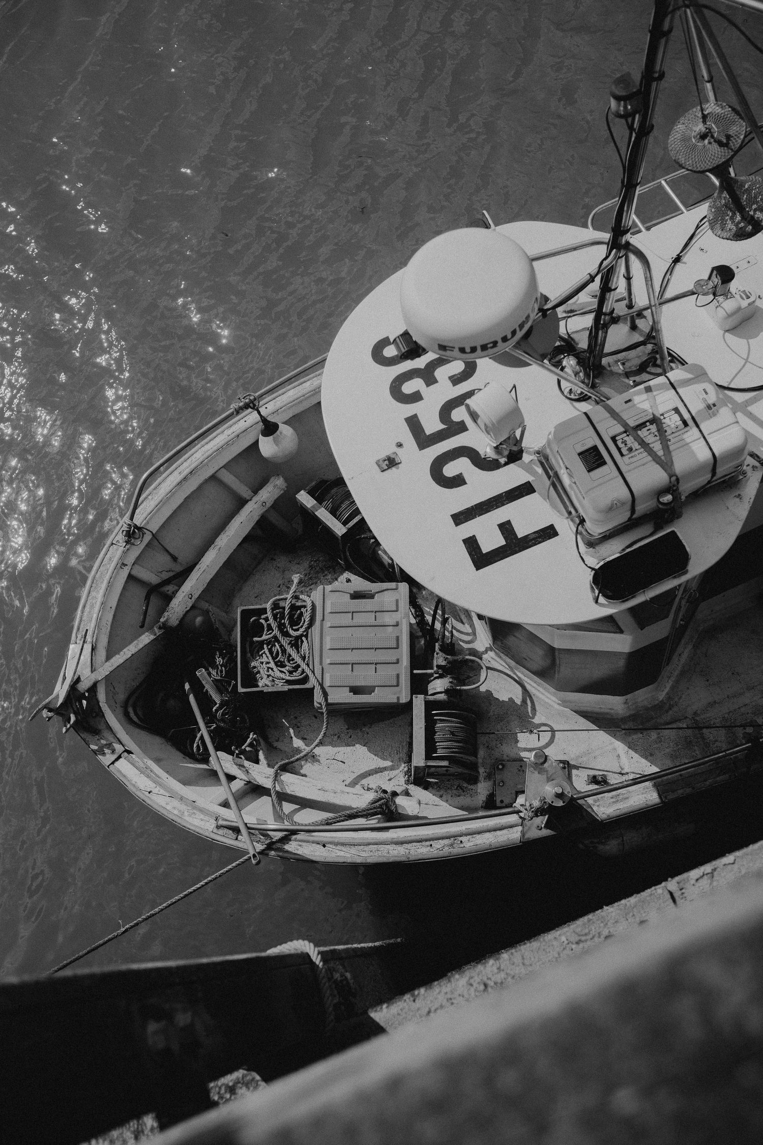 Black and white aerial view of a small fishing boat with identification number FL599 visible on its deck.