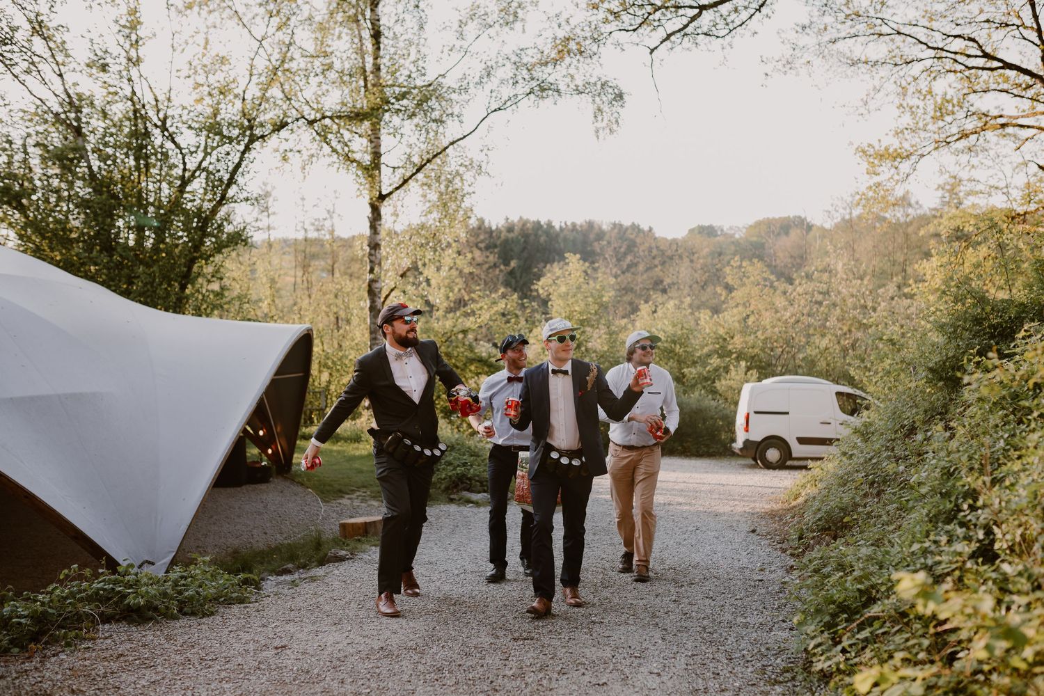Wedding guests arriving at an outdoor event venue along a gravel path surrounded by autumn foliage.