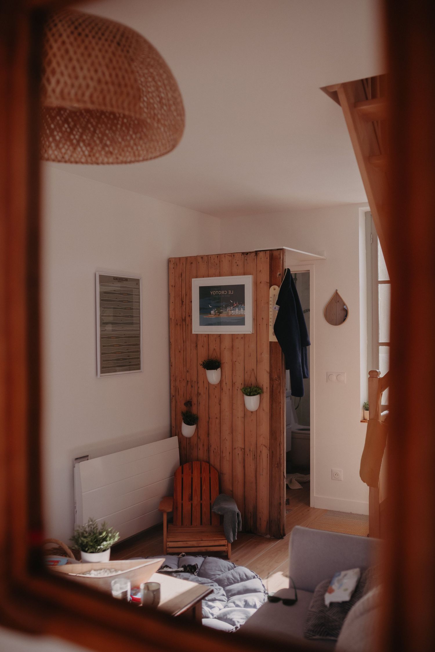 Cozy interior corner with wooden paneling, rattan pendant lamp, and modern furniture in warm ambient lighting.