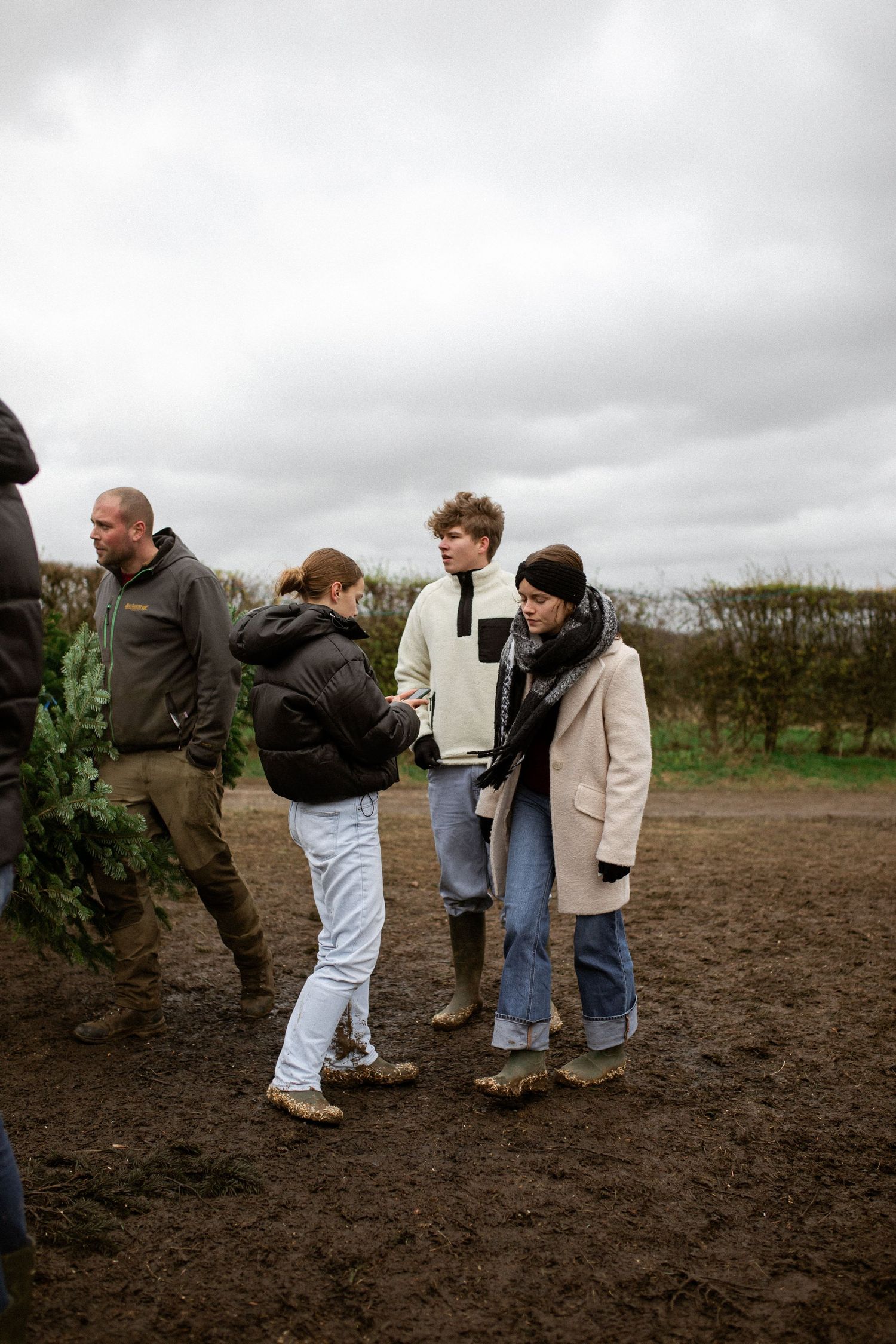 A group of people standing together on a dirt path on an overcast day in the countryside.