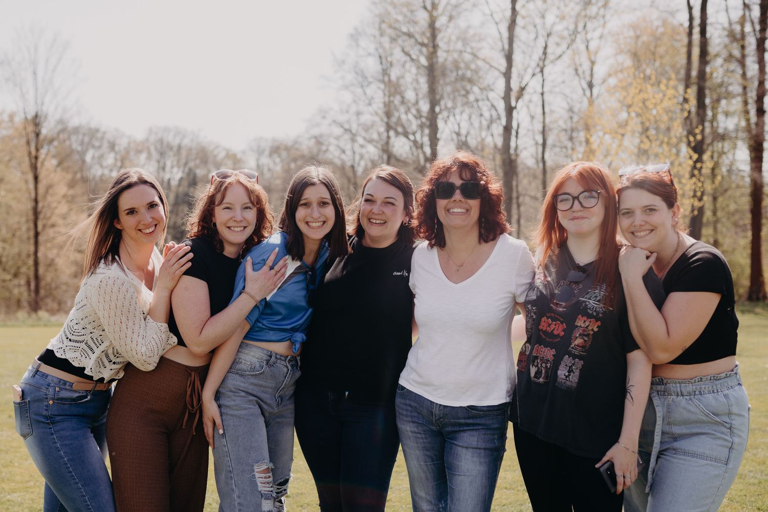 Group standing together outdoors against a backdrop of autumn trees on a sunny day.