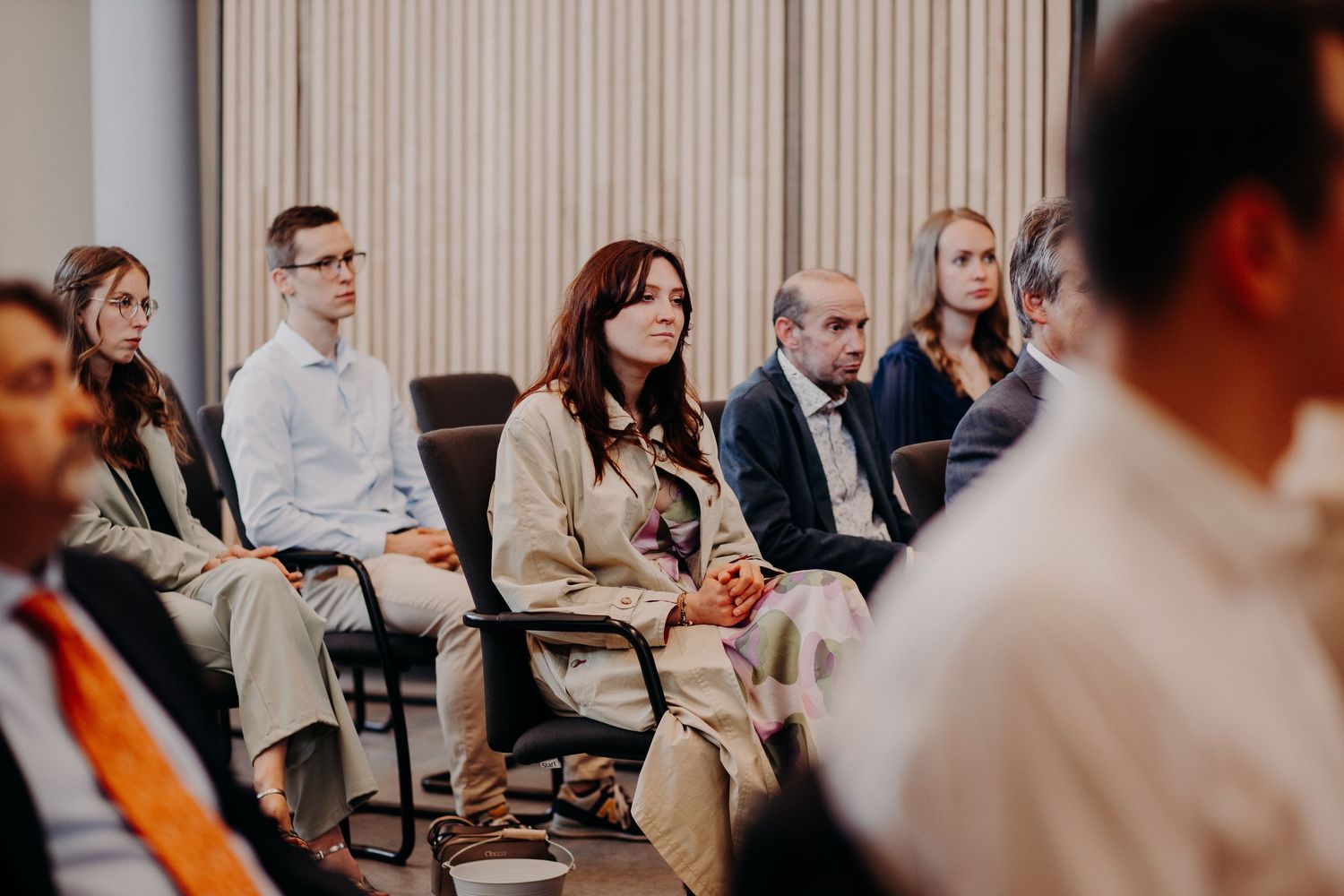 A group of people sit in chairs during a small indoor gathering or meeting.