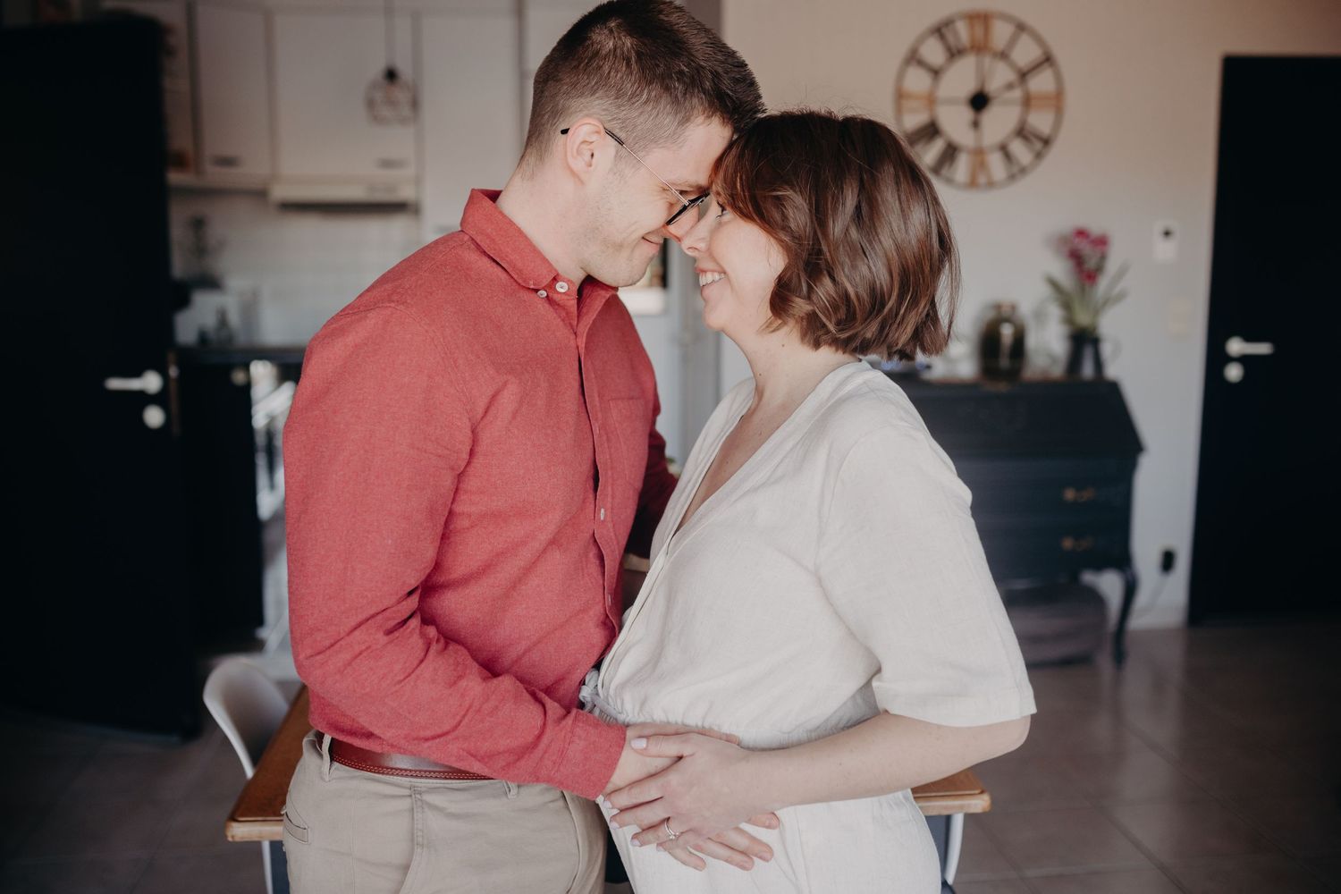 Intimate couple sharing tender moment in modern kitchen setting with rustic decor and natural lighting.