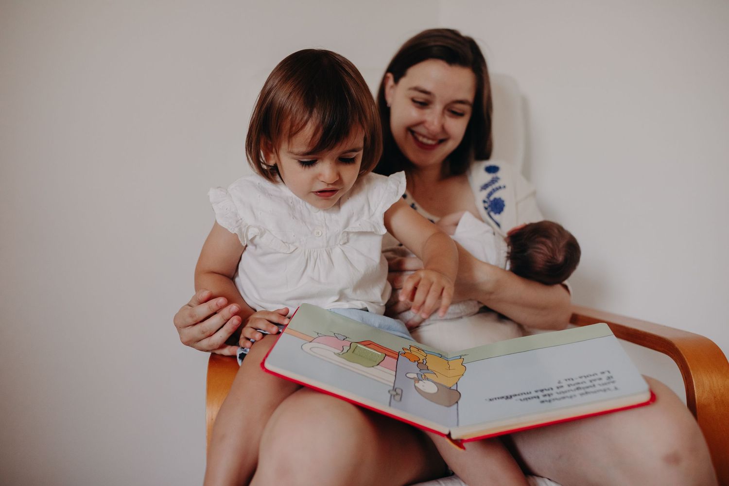 A parent and child share a tender moment reading a picture book together on a white background.