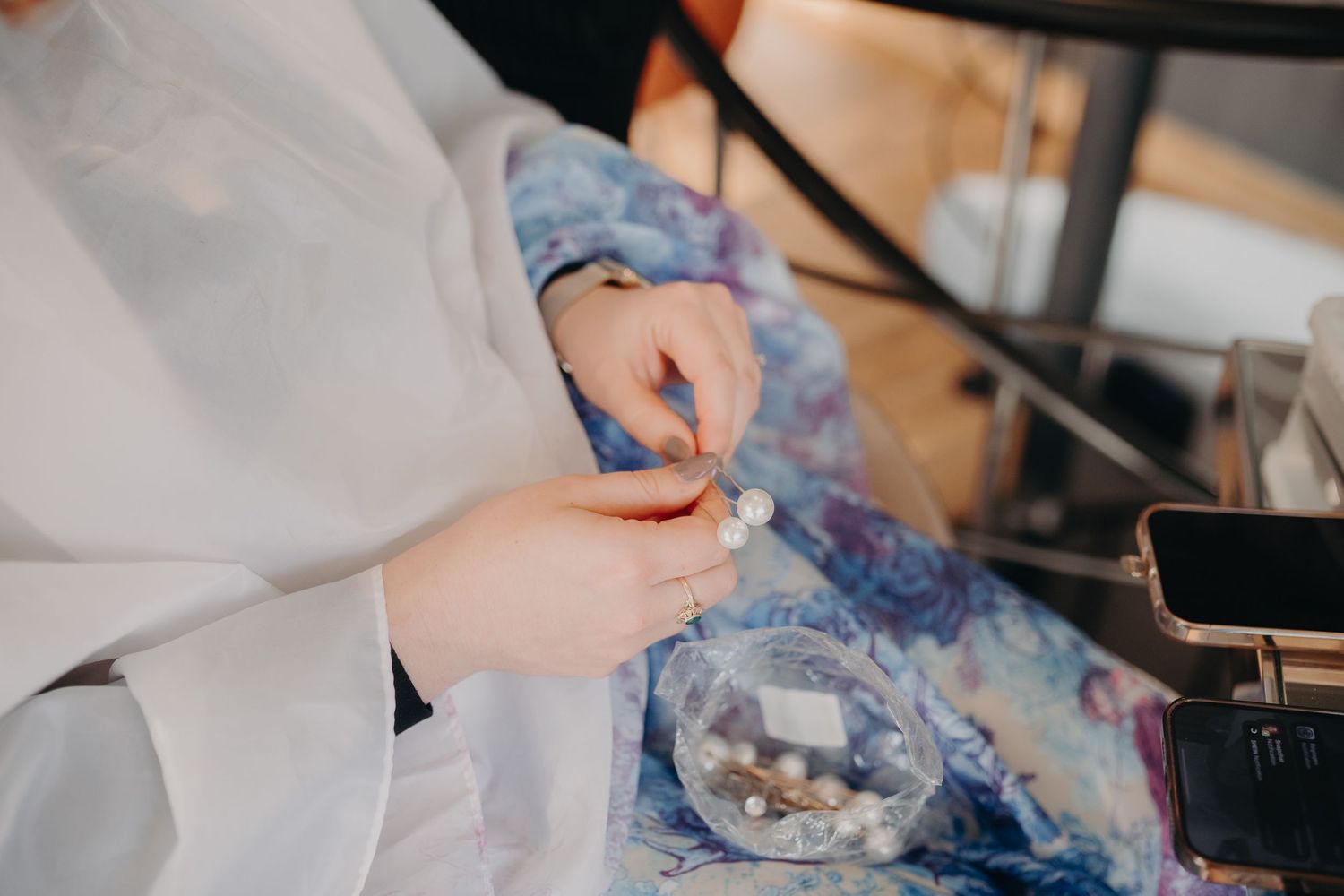 Close-up view of hands in white sleeves preparing ingredients at a workstation with blue fabric in the background.
