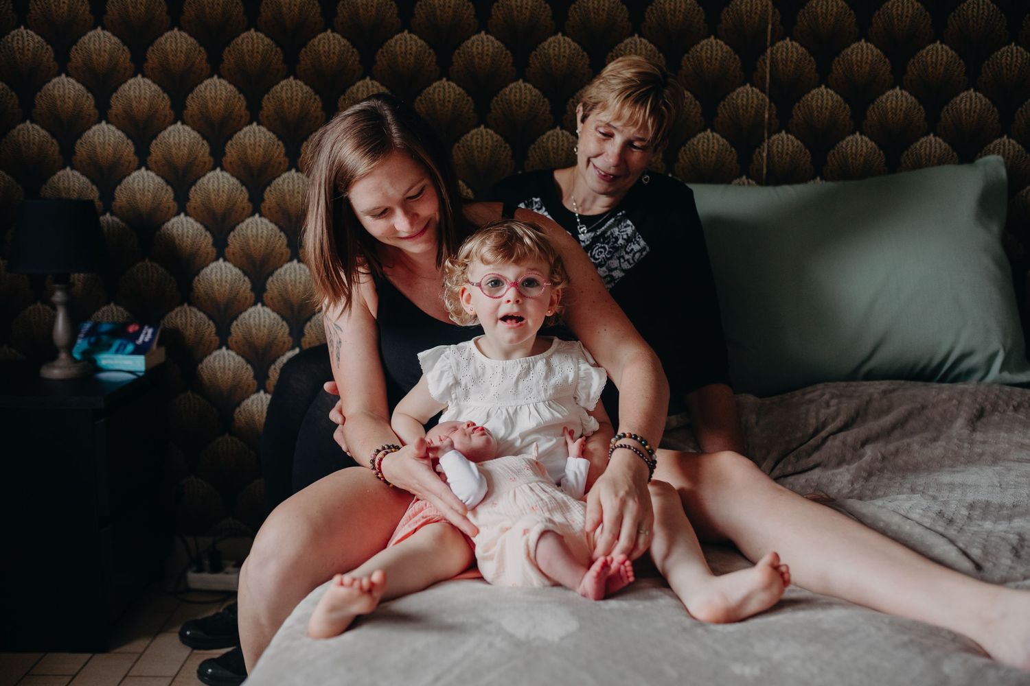 Family spending relaxed time together on a cozy bed with tufted headboard in dimly lit room.