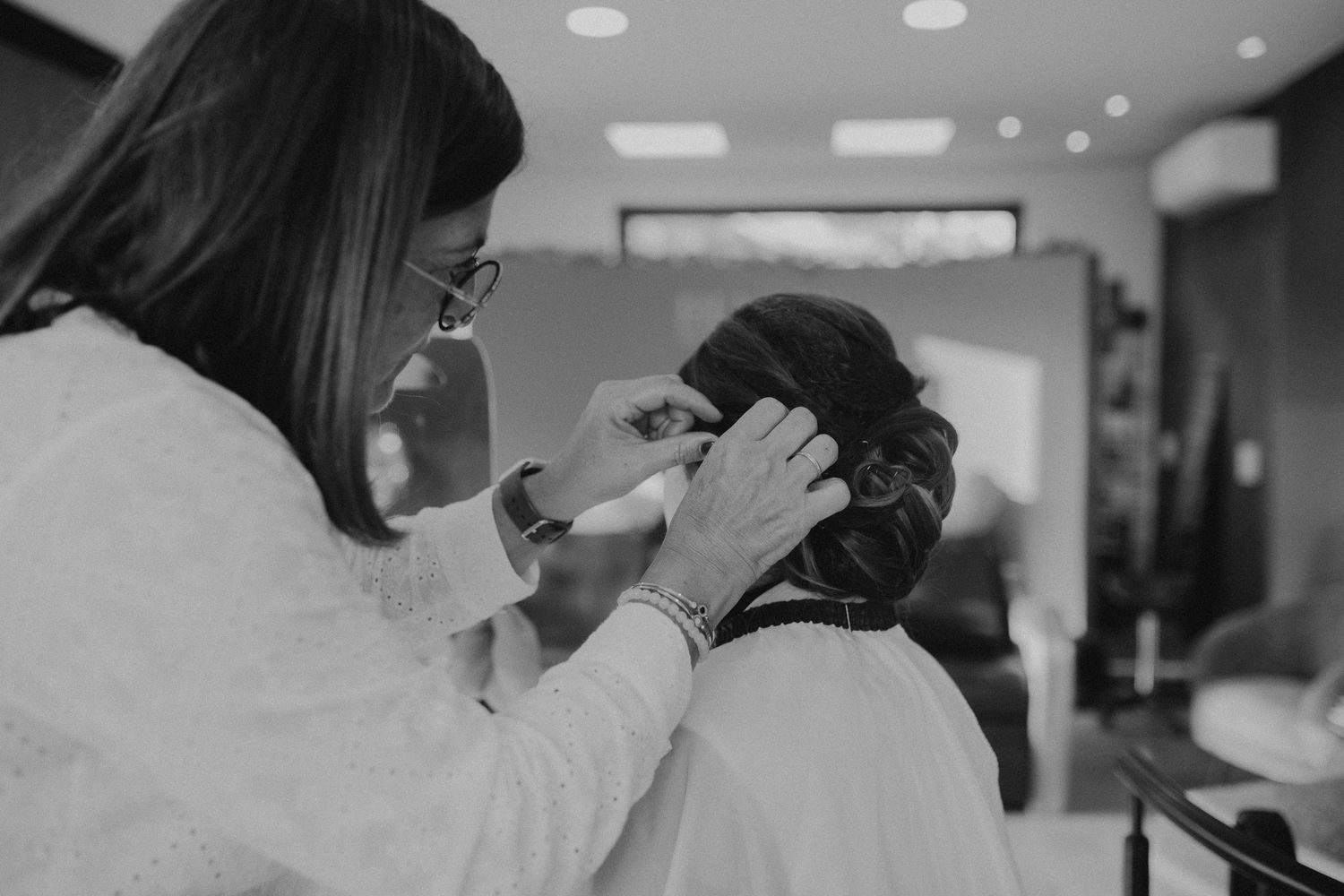 Professional hairstylist working on a client's hair in a modern salon with recessed lighting.