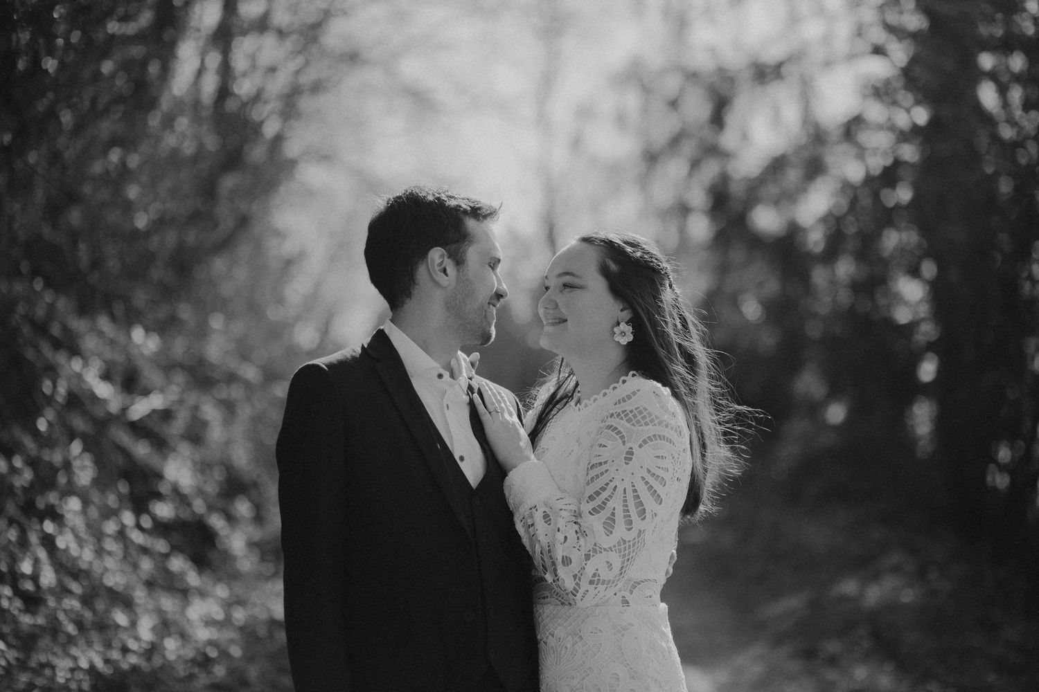 A romantic black and white wedding photo of a couple sharing an intimate moment together in a wooded setting.
