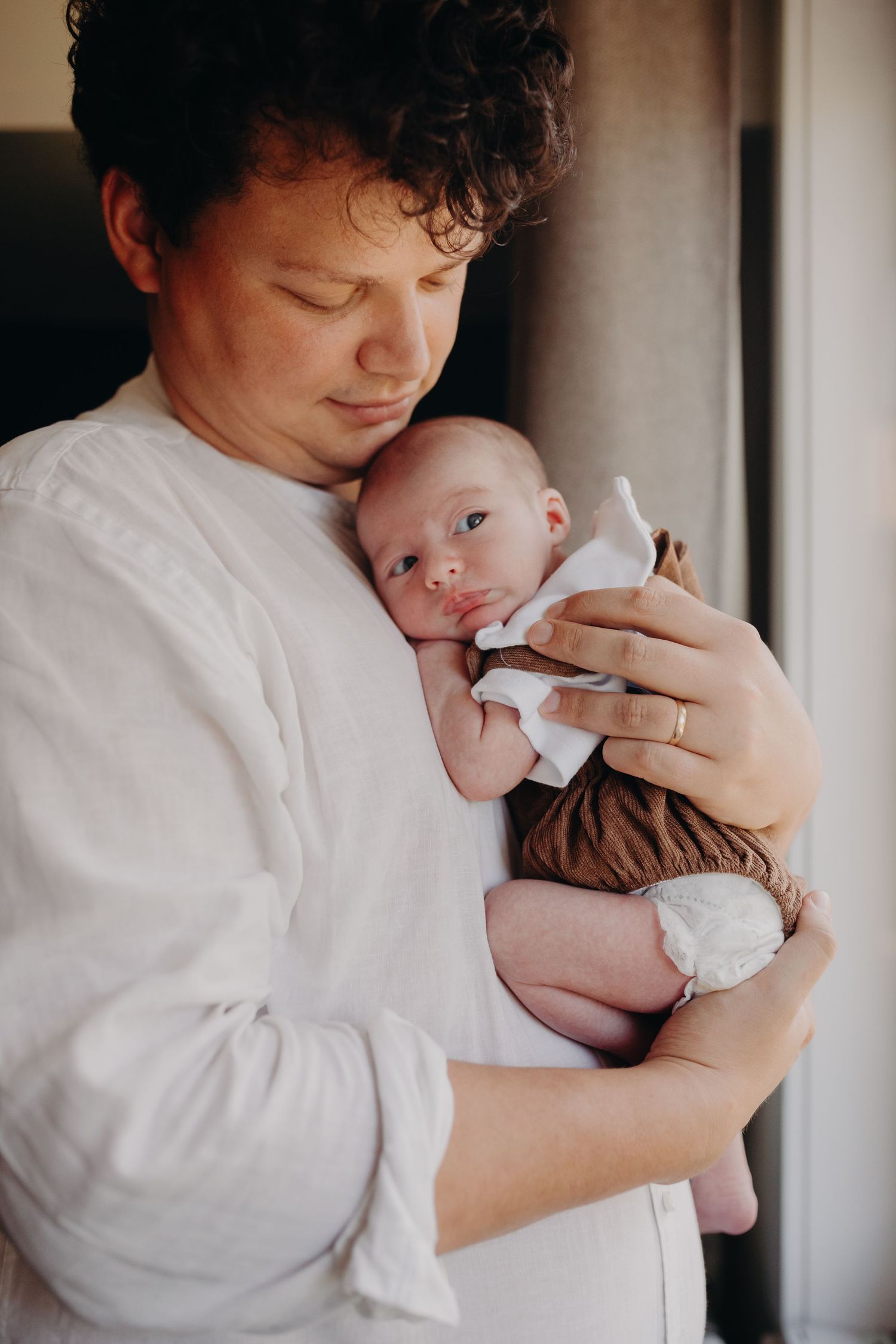 A tender moment captured in a series of five intimate portraits showing gentle embraces with a newborn baby.