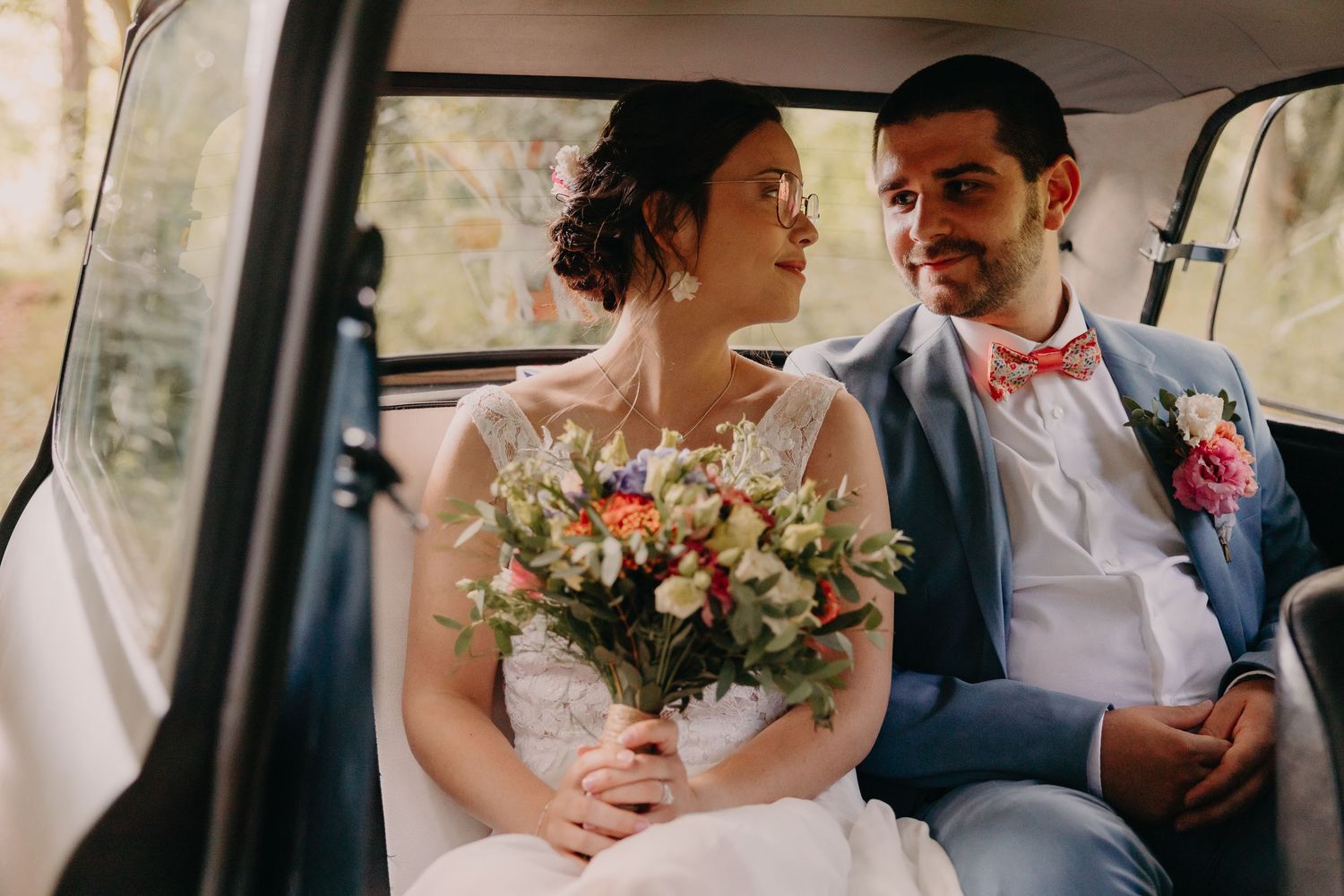 Romantic wedding couple moments captured in vintage car and outdoor settings with floral bouquet.