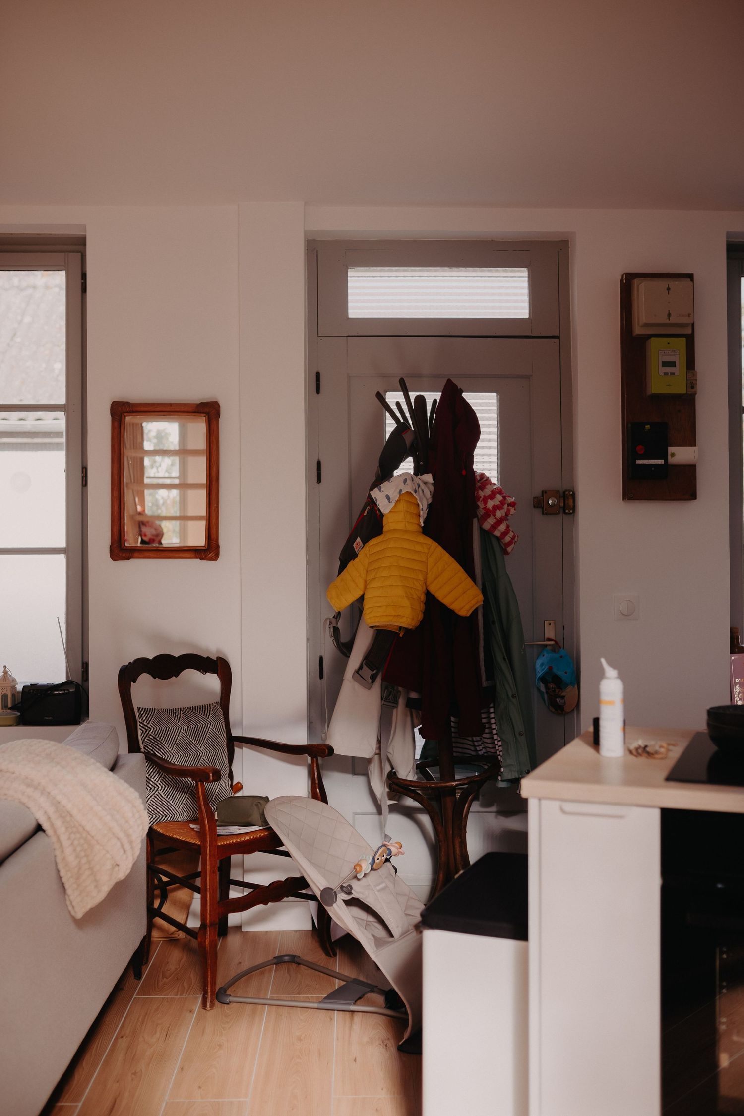 Interior view of a cozy room with wooden chair, coat rack, and yellow sweater hanging in a minimalist space.