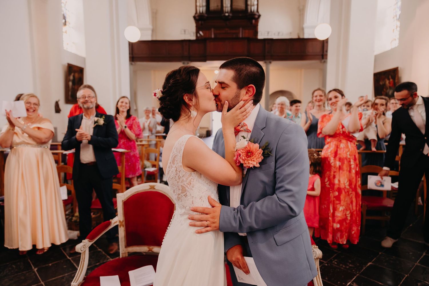 Joyful wedding reception scene with couples dancing and celebrating in an elegant white-draped venue.