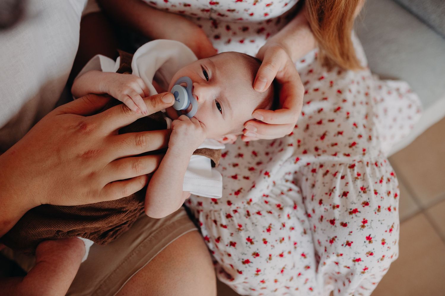 A sequence of images showing a baby being fed from a bottle in a white onesie with small red hearts.