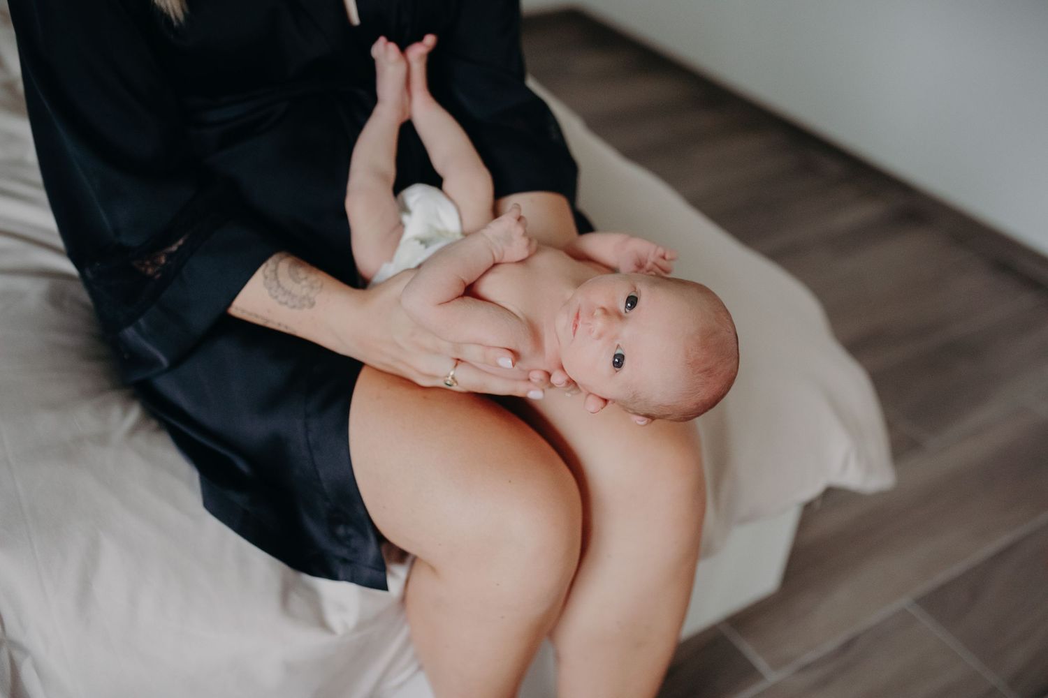 A baby lies on their back on a soft surface while receiving gentle care and attention.