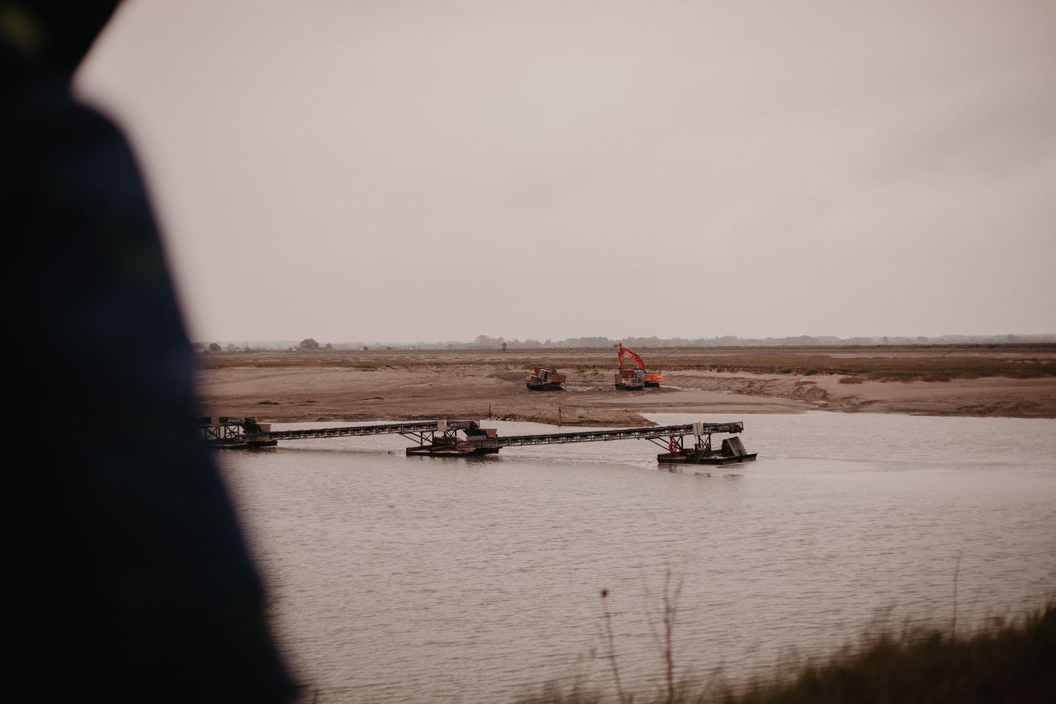 Small boats navigate across calm waterways through a rural landscape at dusk.