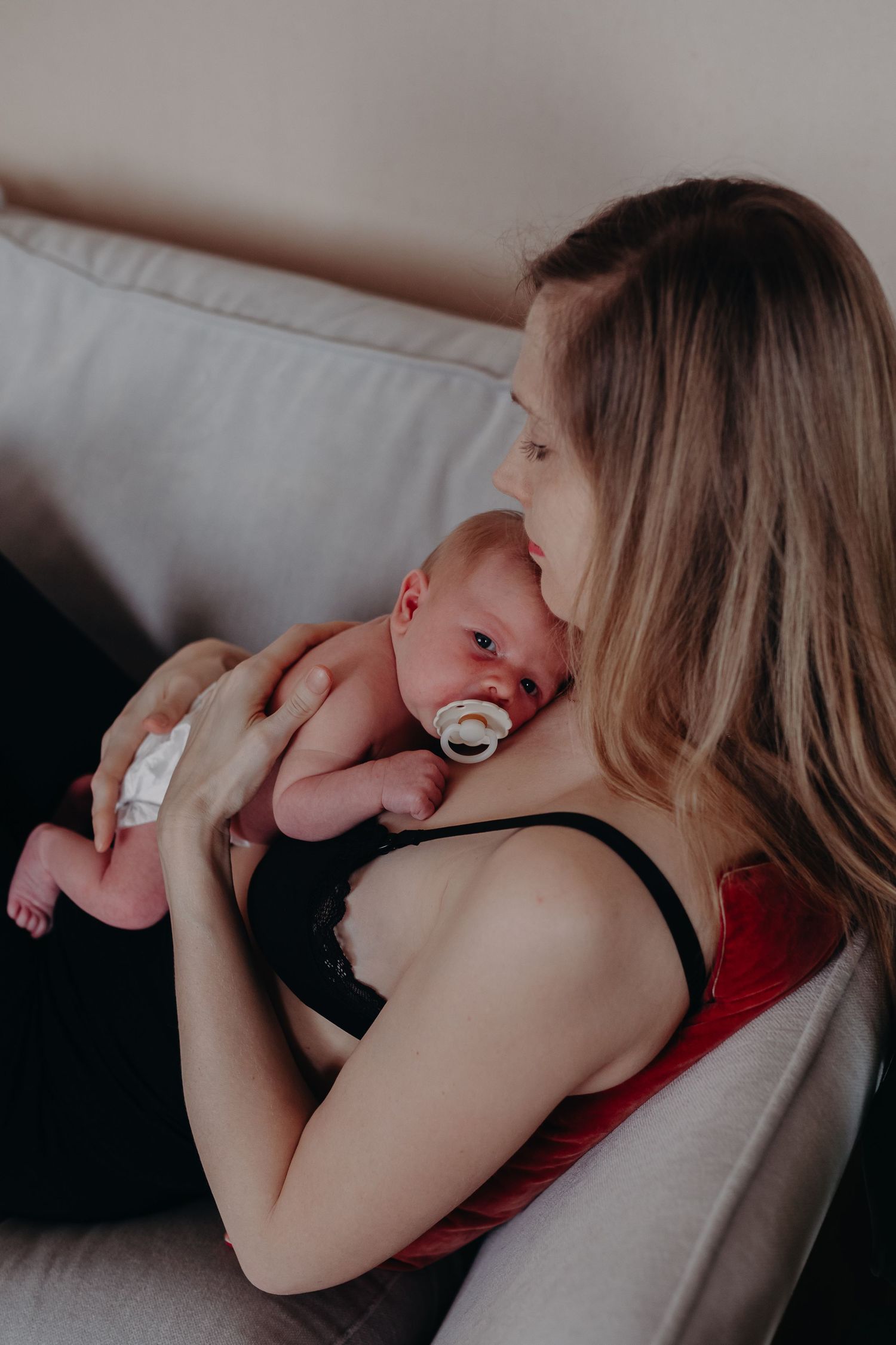A series of intimate nursing moments captured in soft lighting showing a baby breastfeeding on a couch.