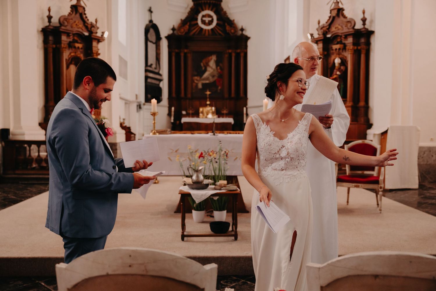 A joyful moment during a wedding ceremony inside a traditional church with ornate wooden altar decorations.