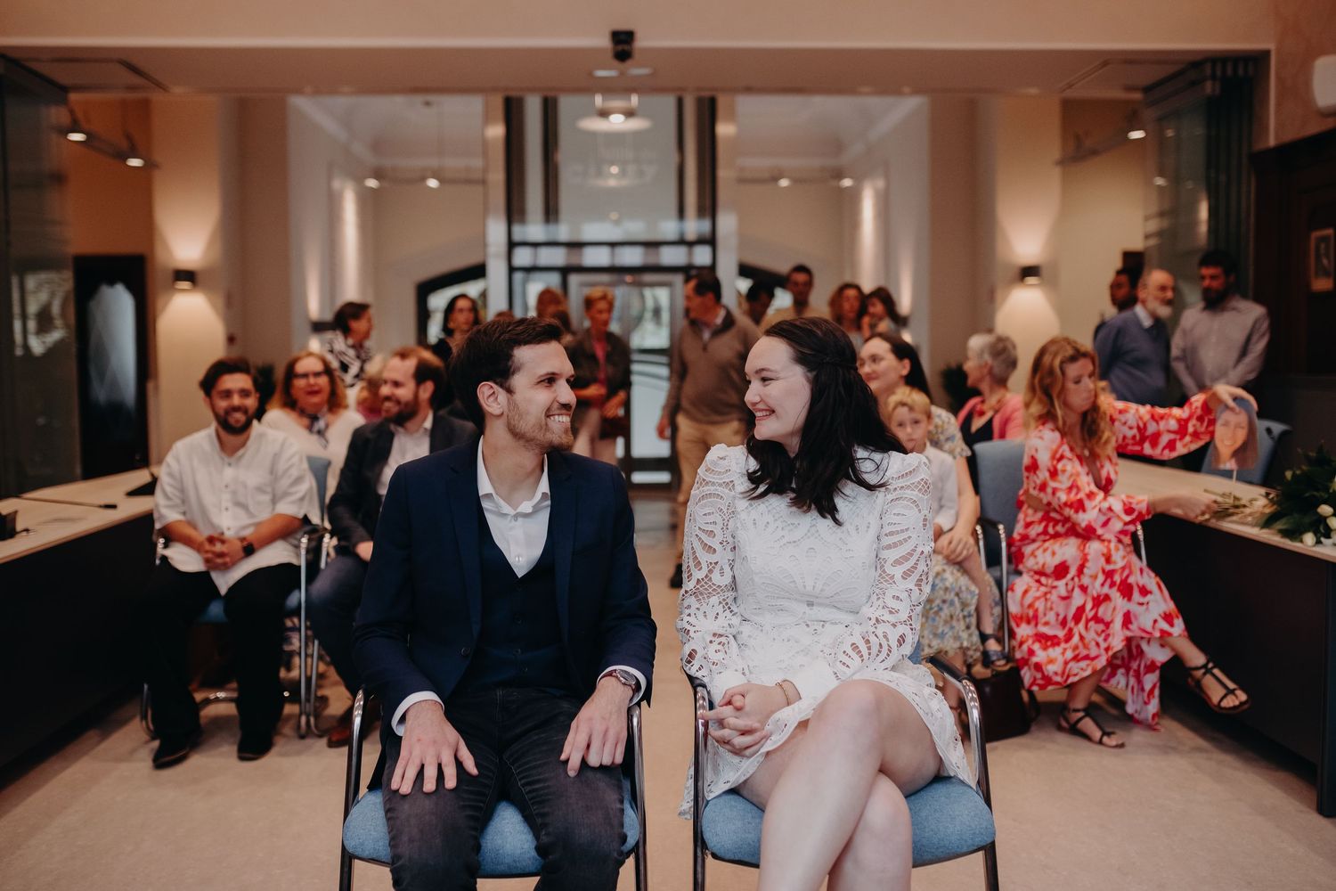 People sitting together at an indoor event while sharing laughter and conversation in a warm social setting.