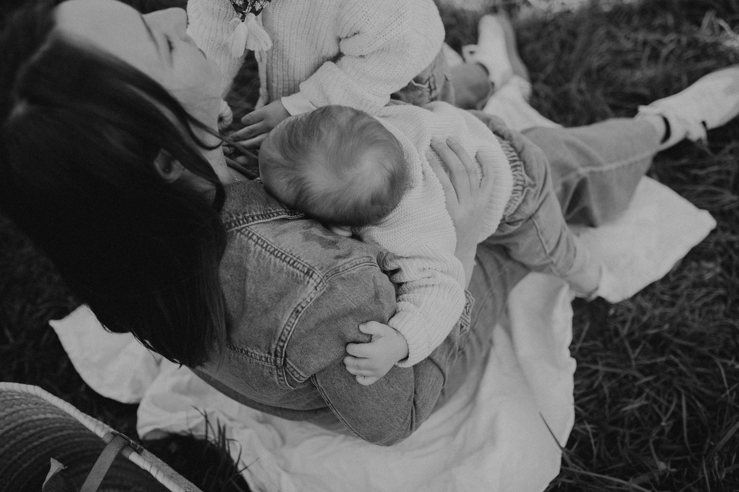 A vintage black and white photograph shows a small child sleeping while resting on blankets outdoors.