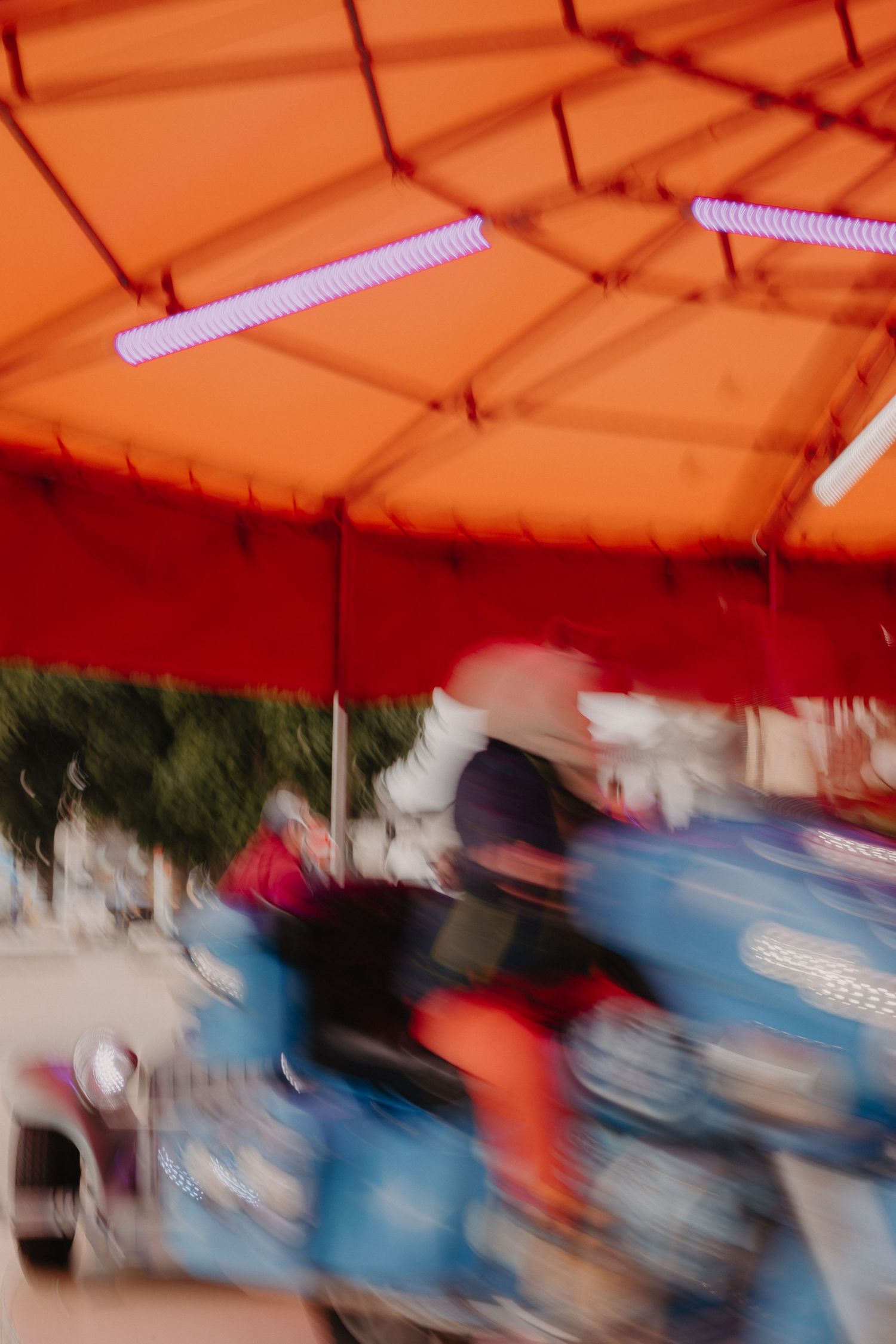 Motion blur of an amusement park ride under an orange canopy showing movement and speed.