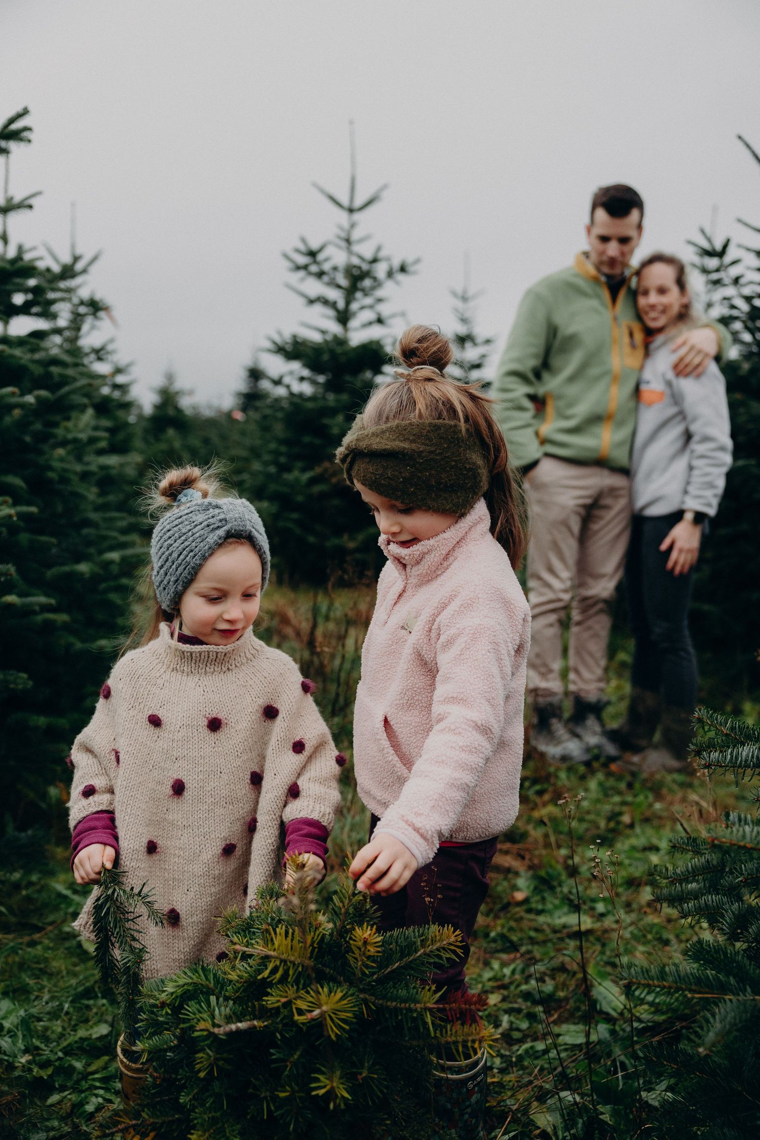 A series of photos showing children exploring a Christmas tree farm in winter while wearing cozy sweaters.