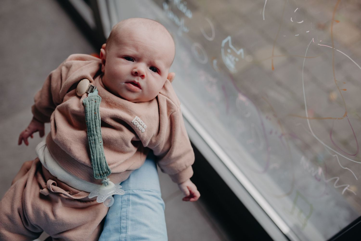 A collection of images showing a baby in light blue clothing resting on a bed near a window.