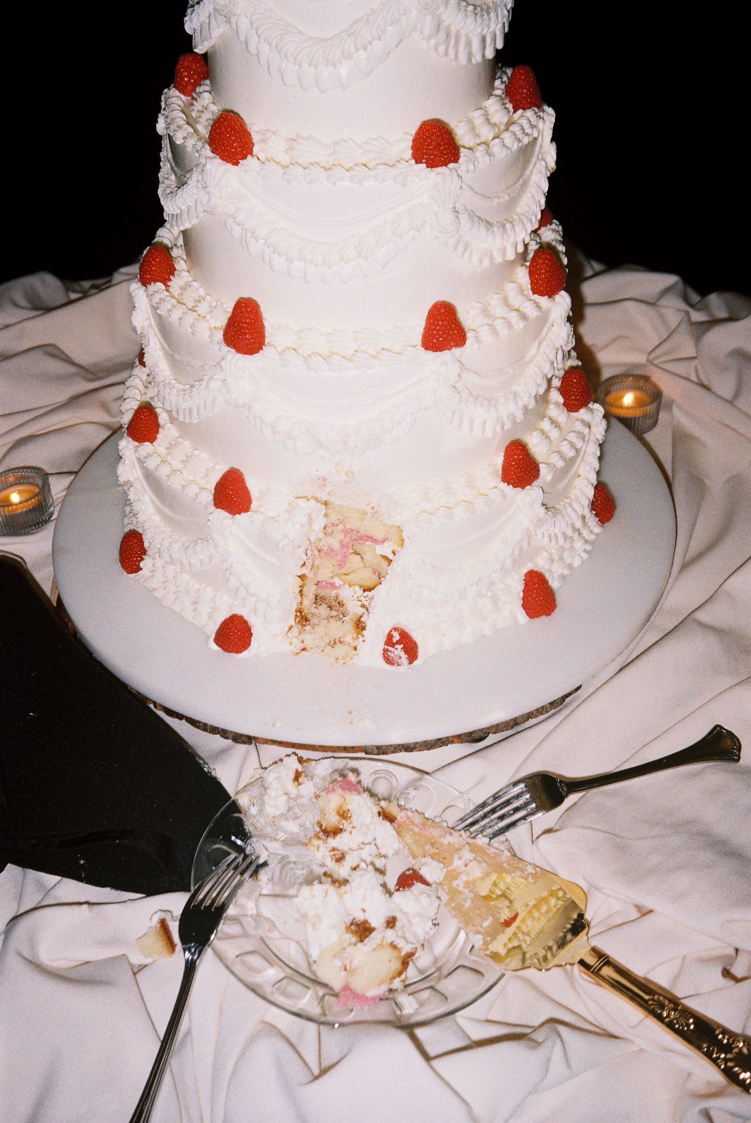 Tiered white wedding cake decorated with red accents.
