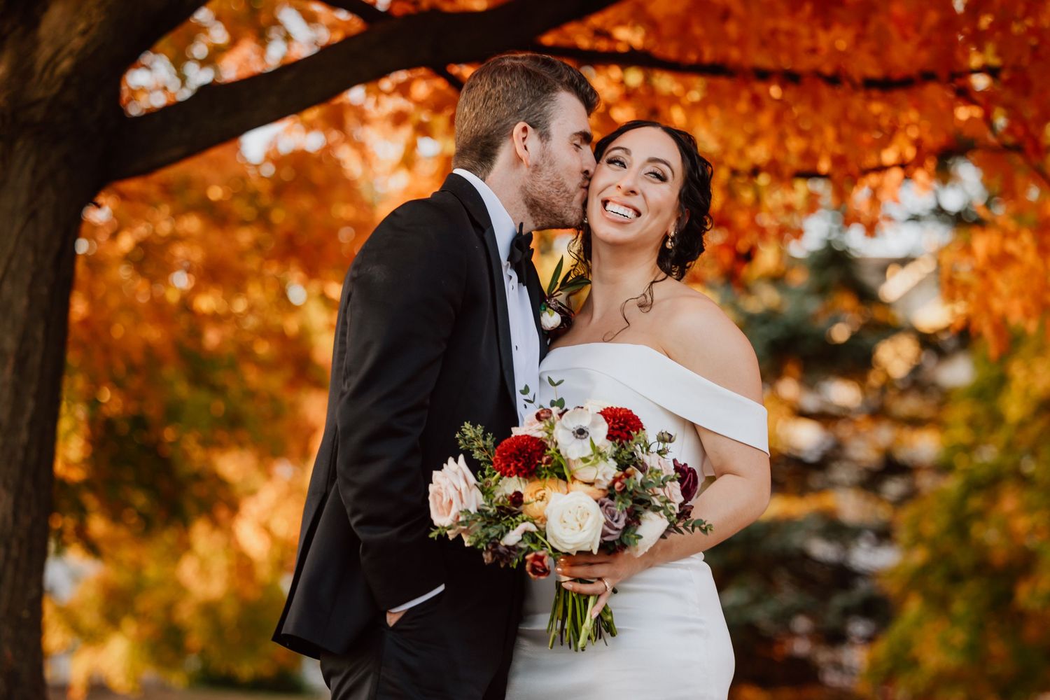 Bride and groom surrounded by warm golden autumn foliage.